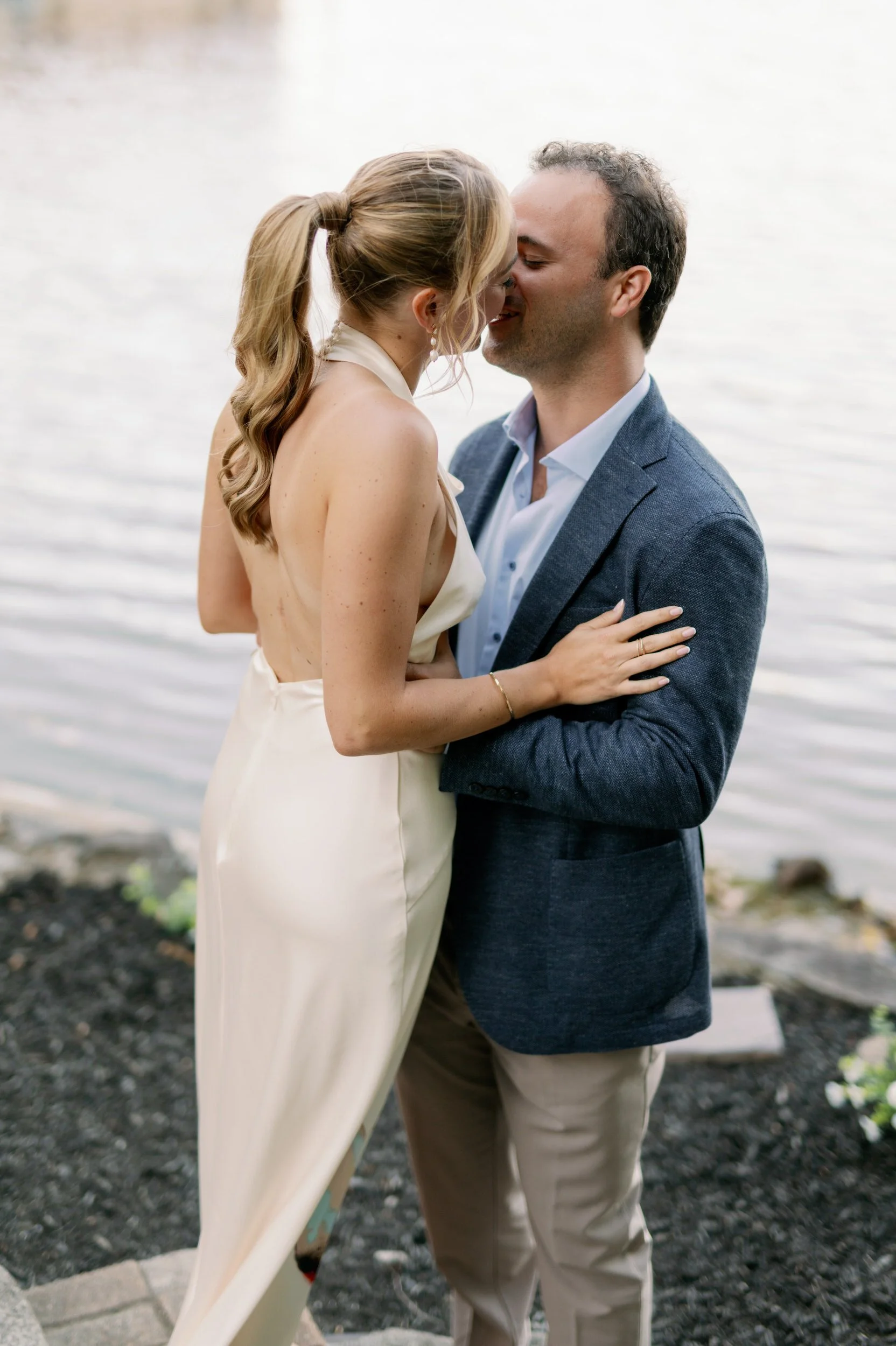 A newlywed couple kissing at the edge of the water