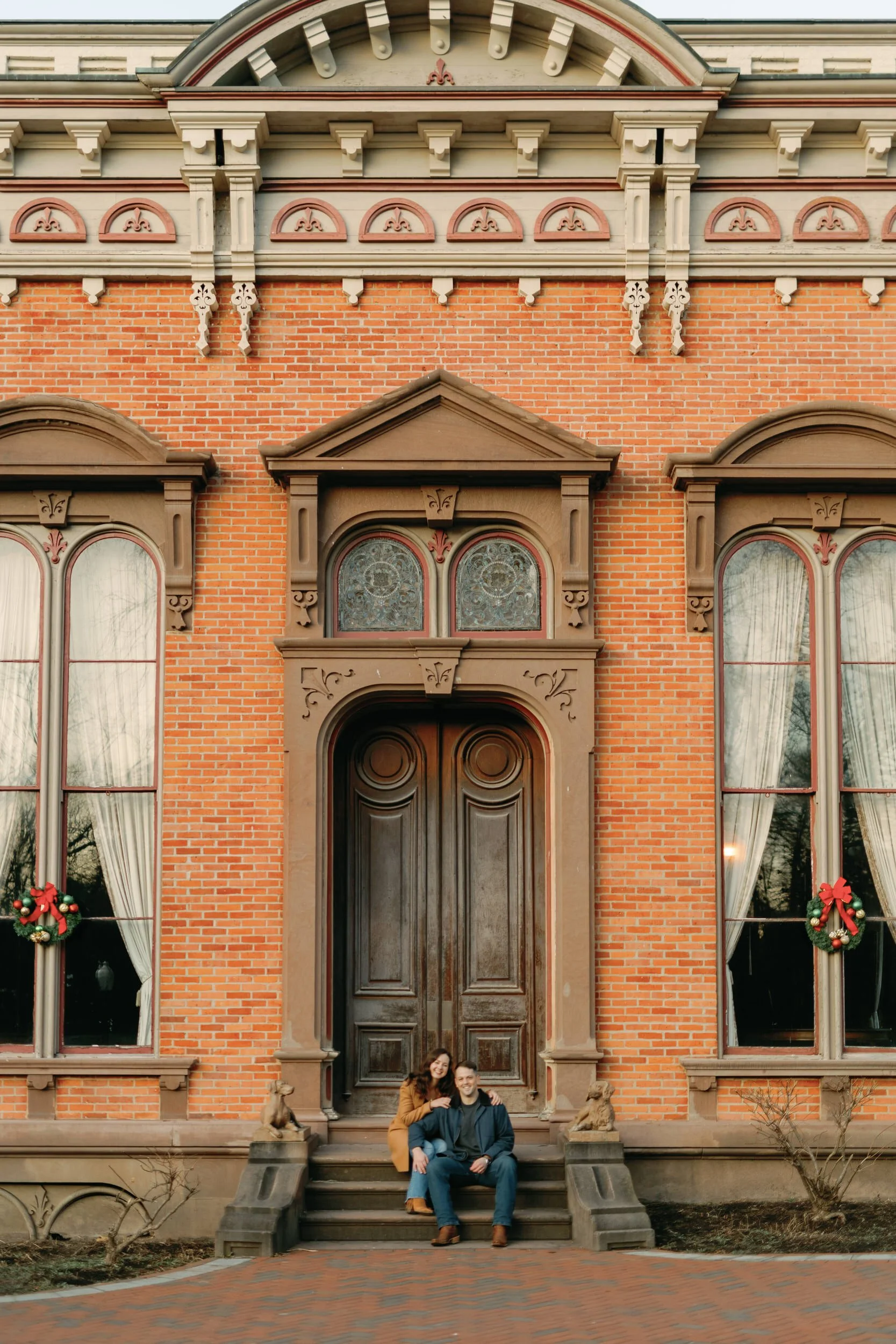 A couple sitting on the steps of a red brick building together 