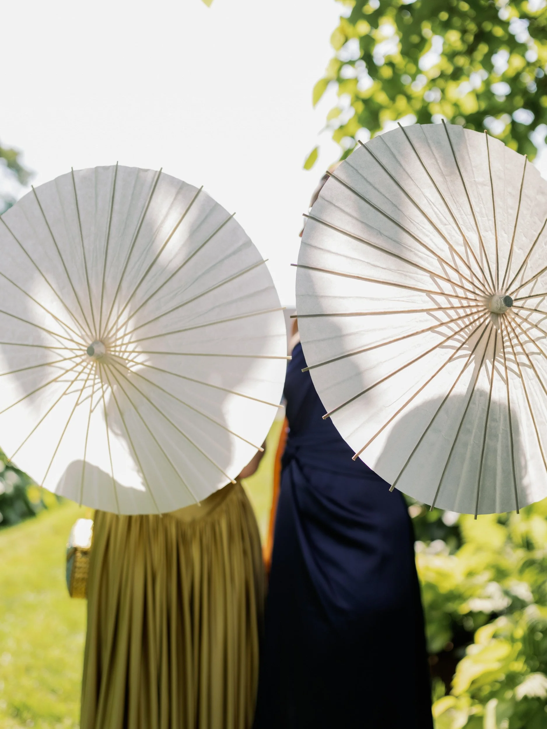 The backs of two people holding decorative umbrellas 