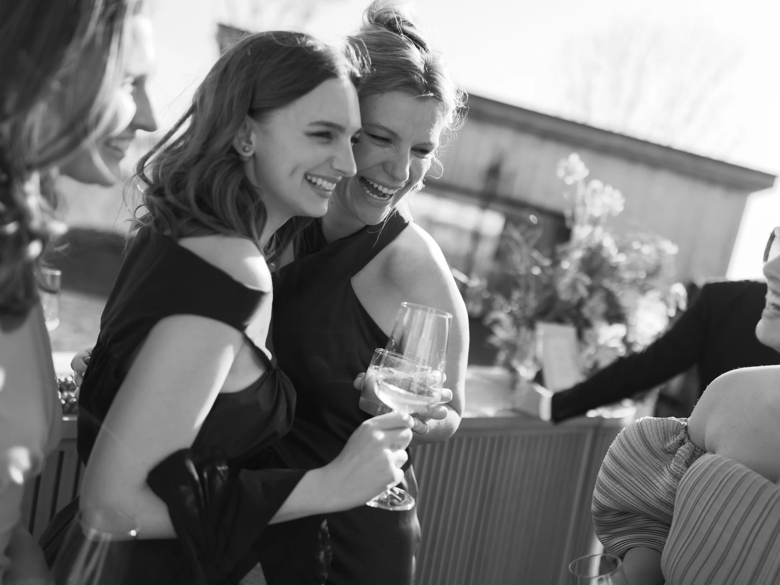 Wedding guests standing close together and laughing during a cocktail hour 