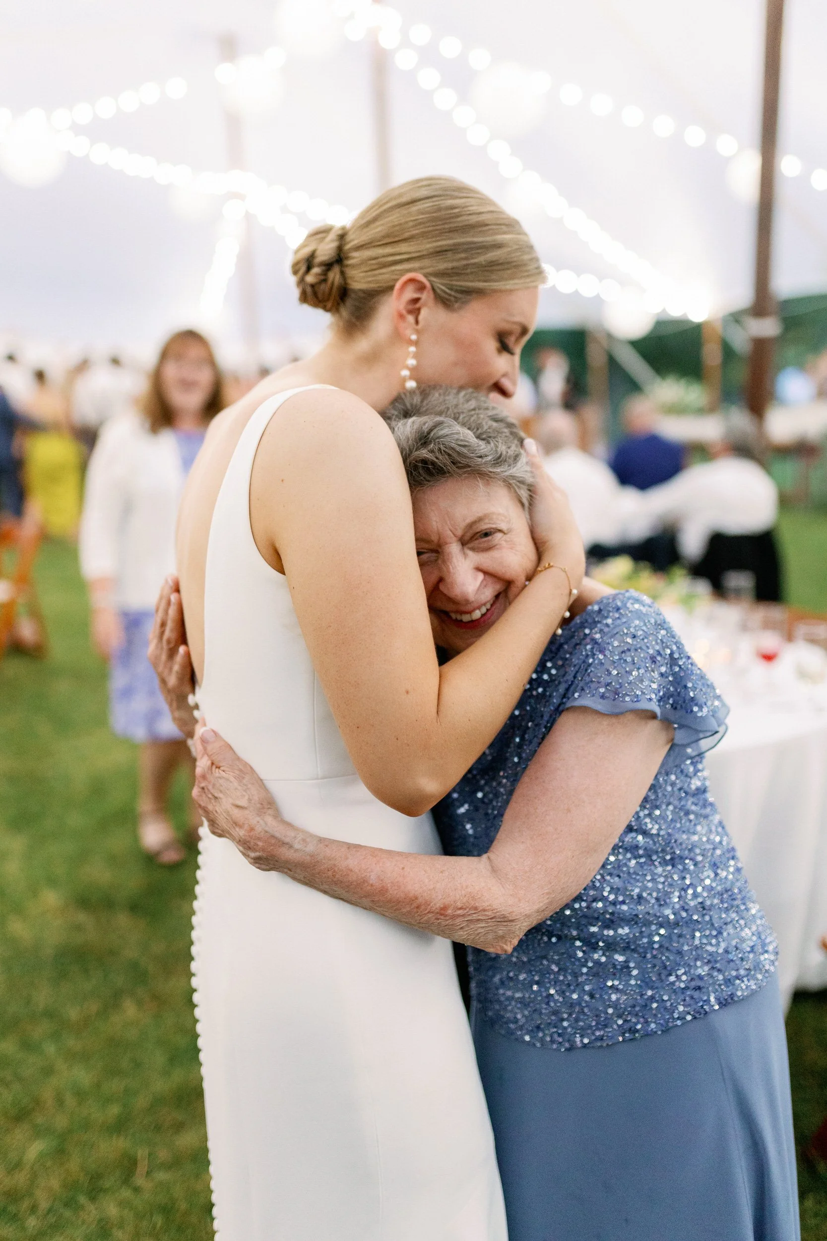  A newlywed in a wedding dress hugging an elderly family member   