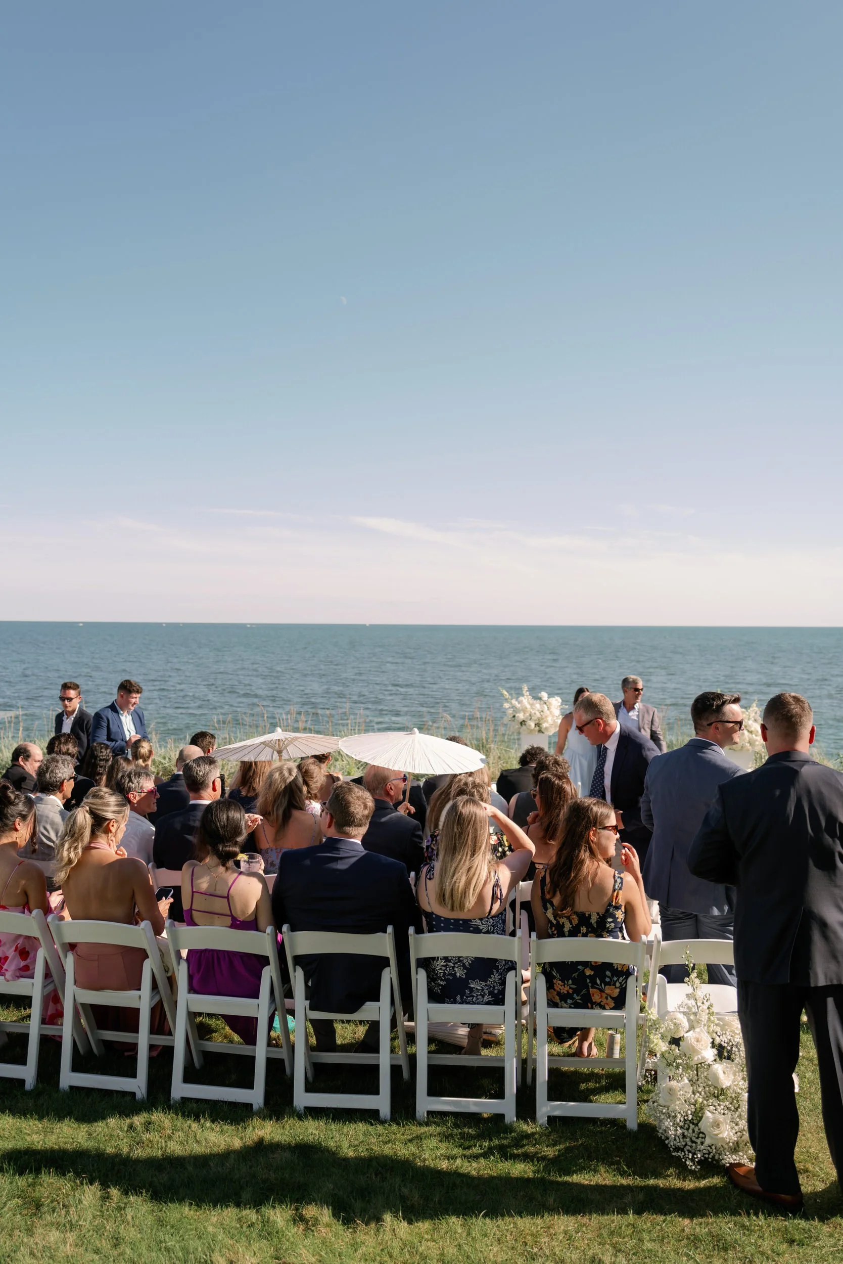 Wedding guests sitting at an outdoor wedding ceremony by the water 
