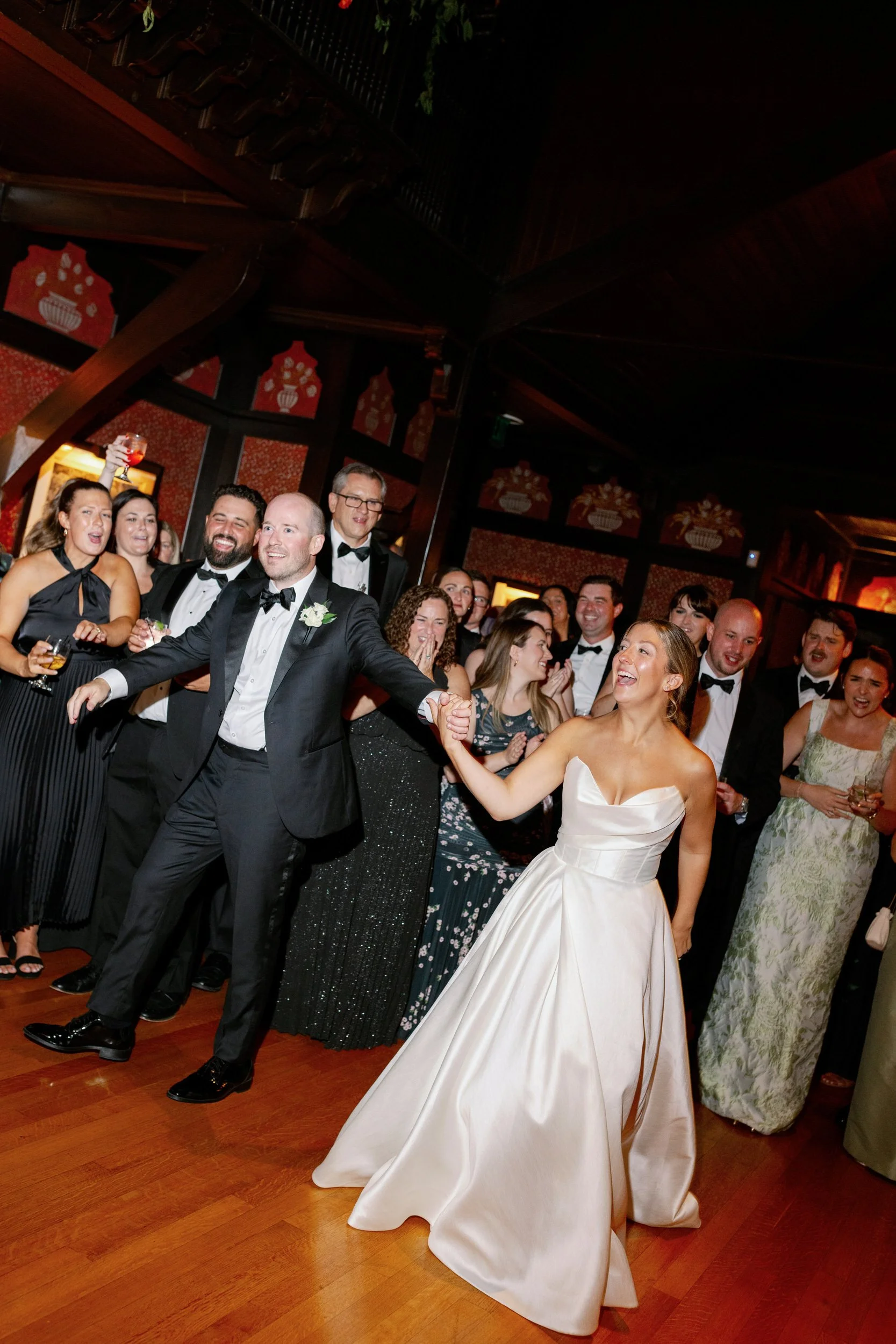Newlyweds holding hands and walking on the dance floor during their reception 