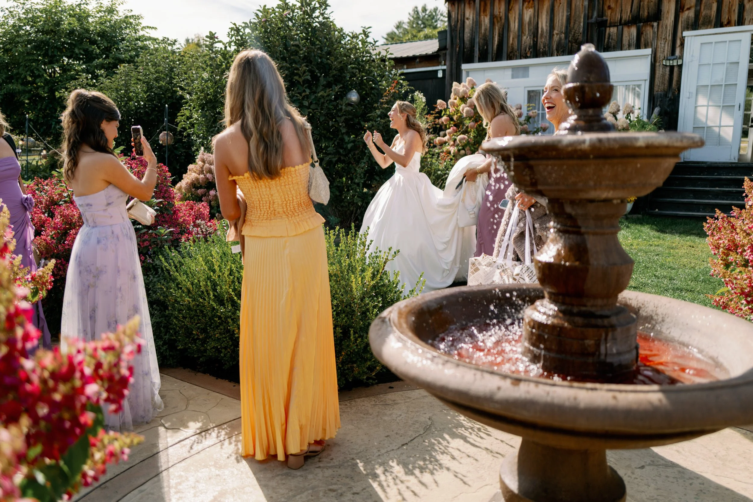 Wedding guests smiling with a newlywed in a garden 