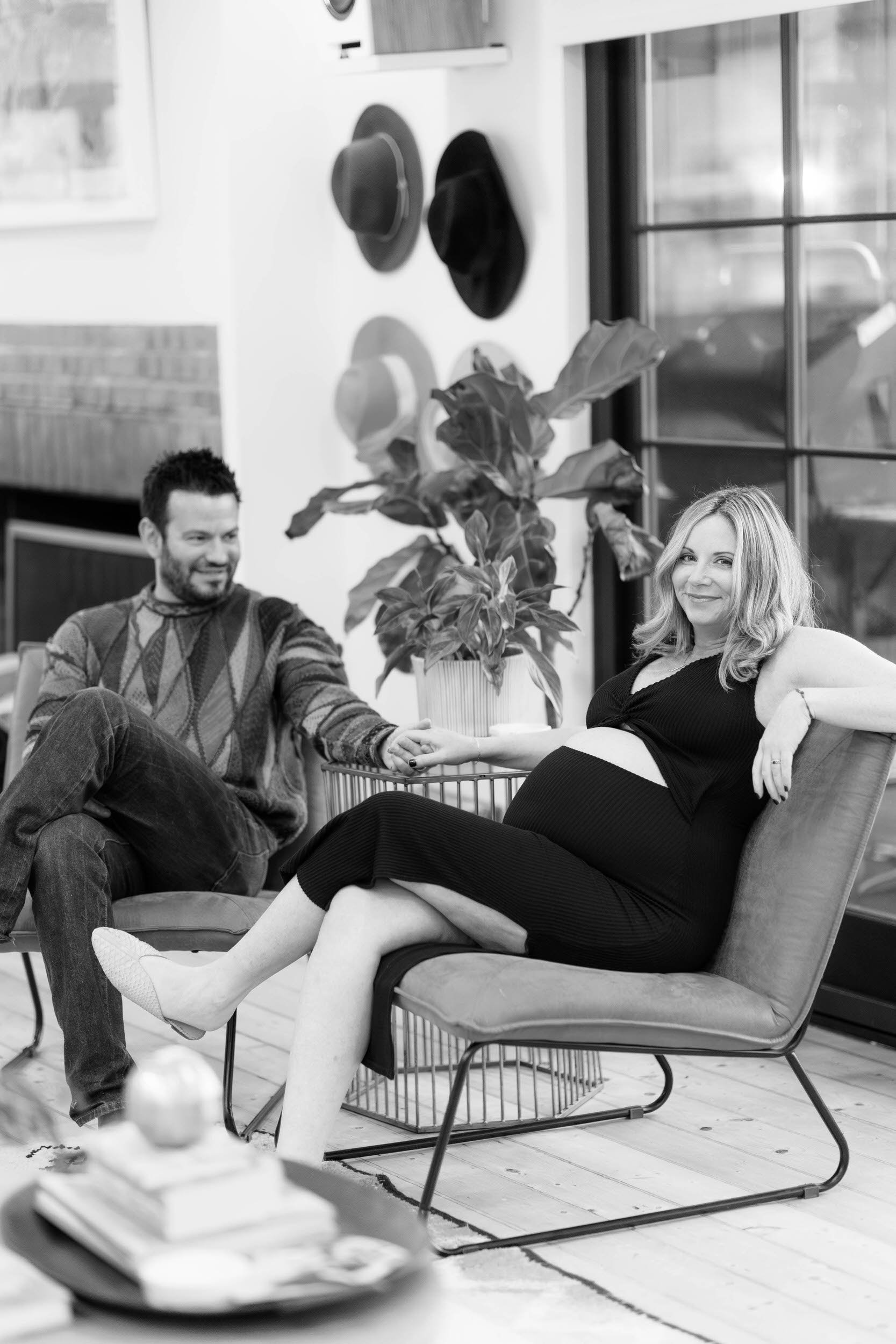 A pregnant person sitting in a chair with their partner sitting next to them 