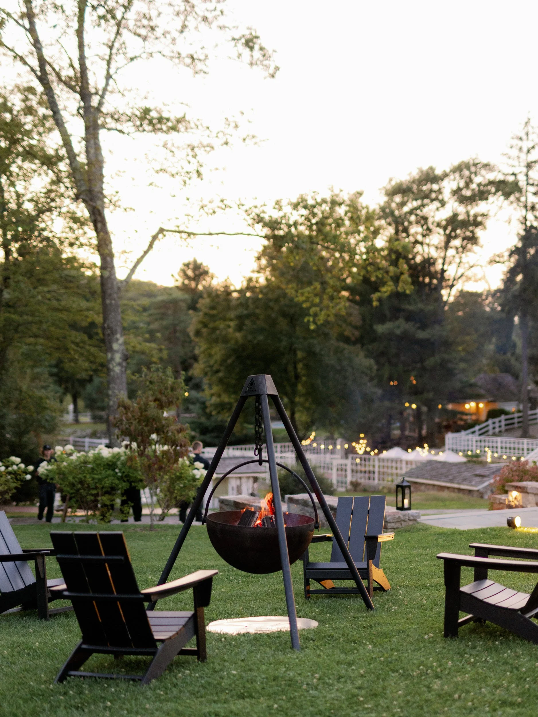 An outdoor area with chair set around a hanging fireplace 