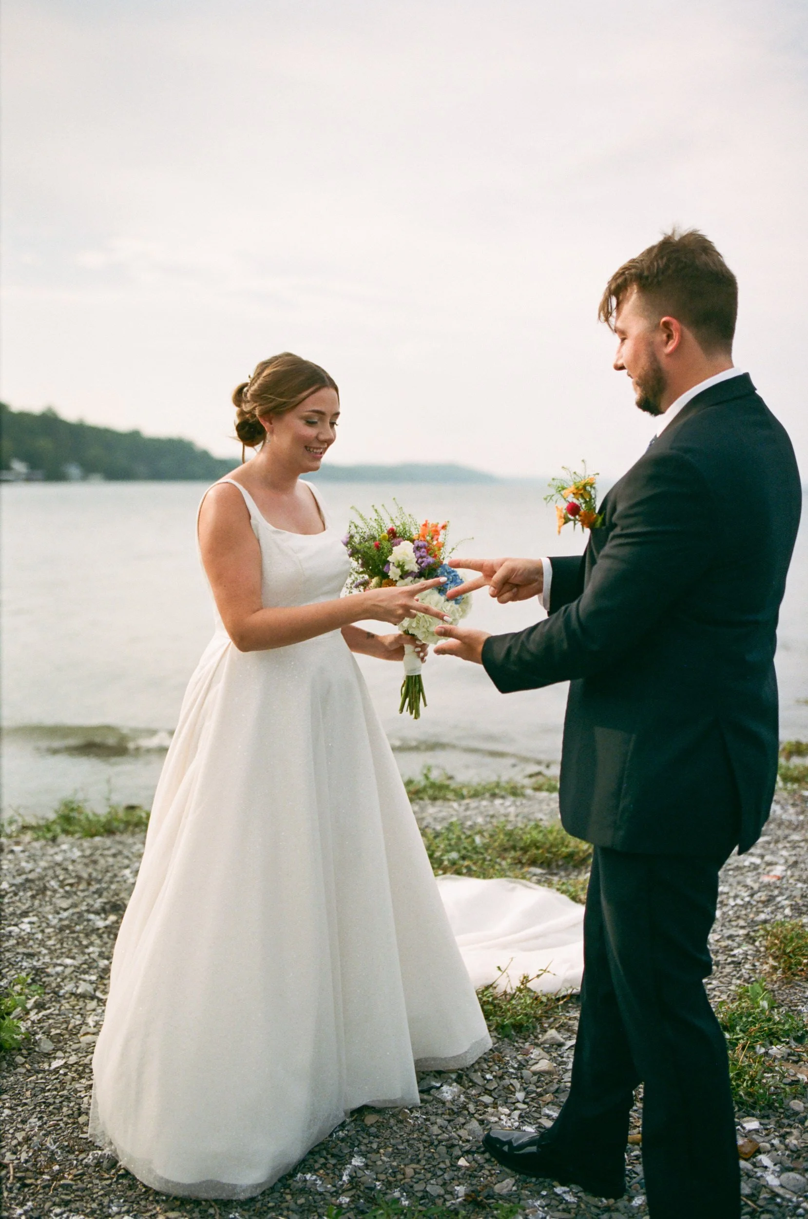 Newlyweds playing rock paper scissors on the edge of the water 