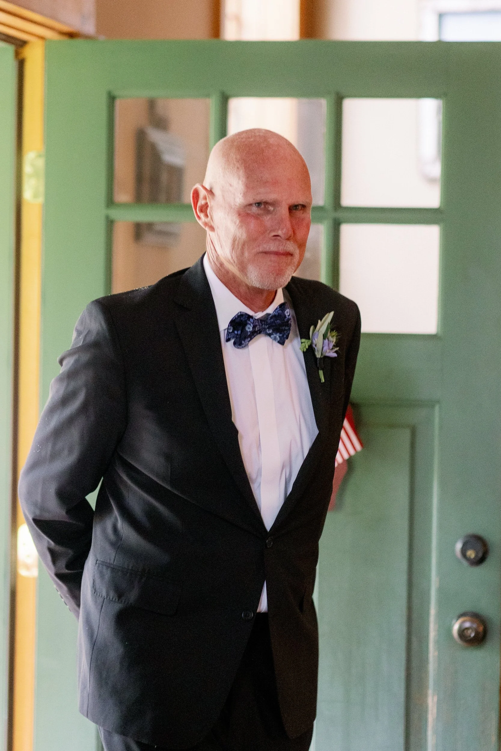 A person in a suit walking through a door with a smile 