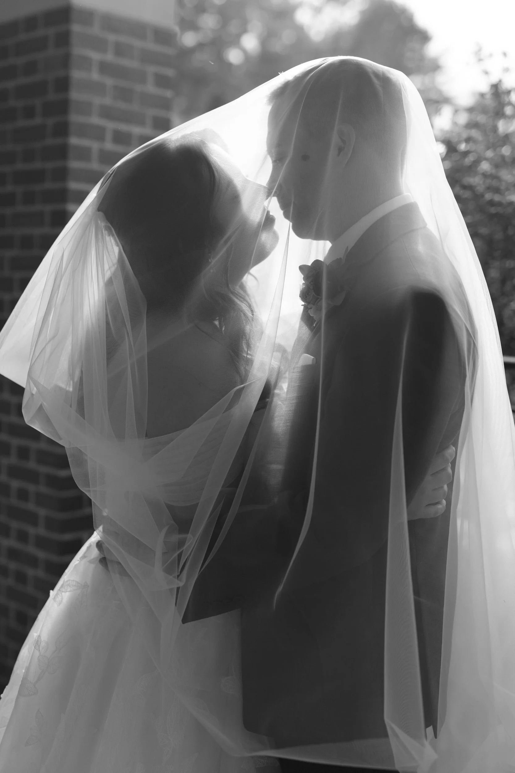 newlyweds leaning in to kiss under a veil 