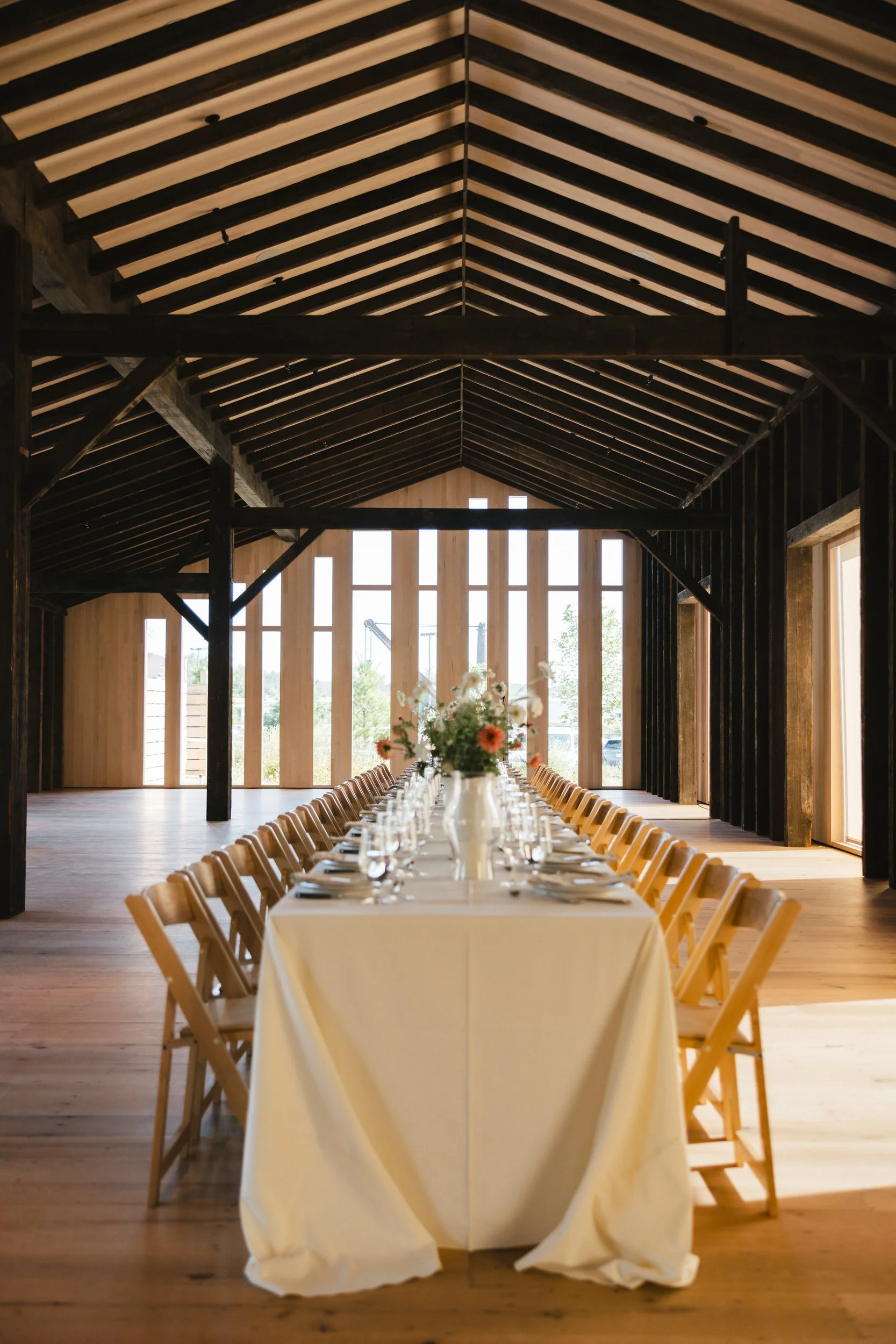 A long wedding reception table set up in a modern style barn 