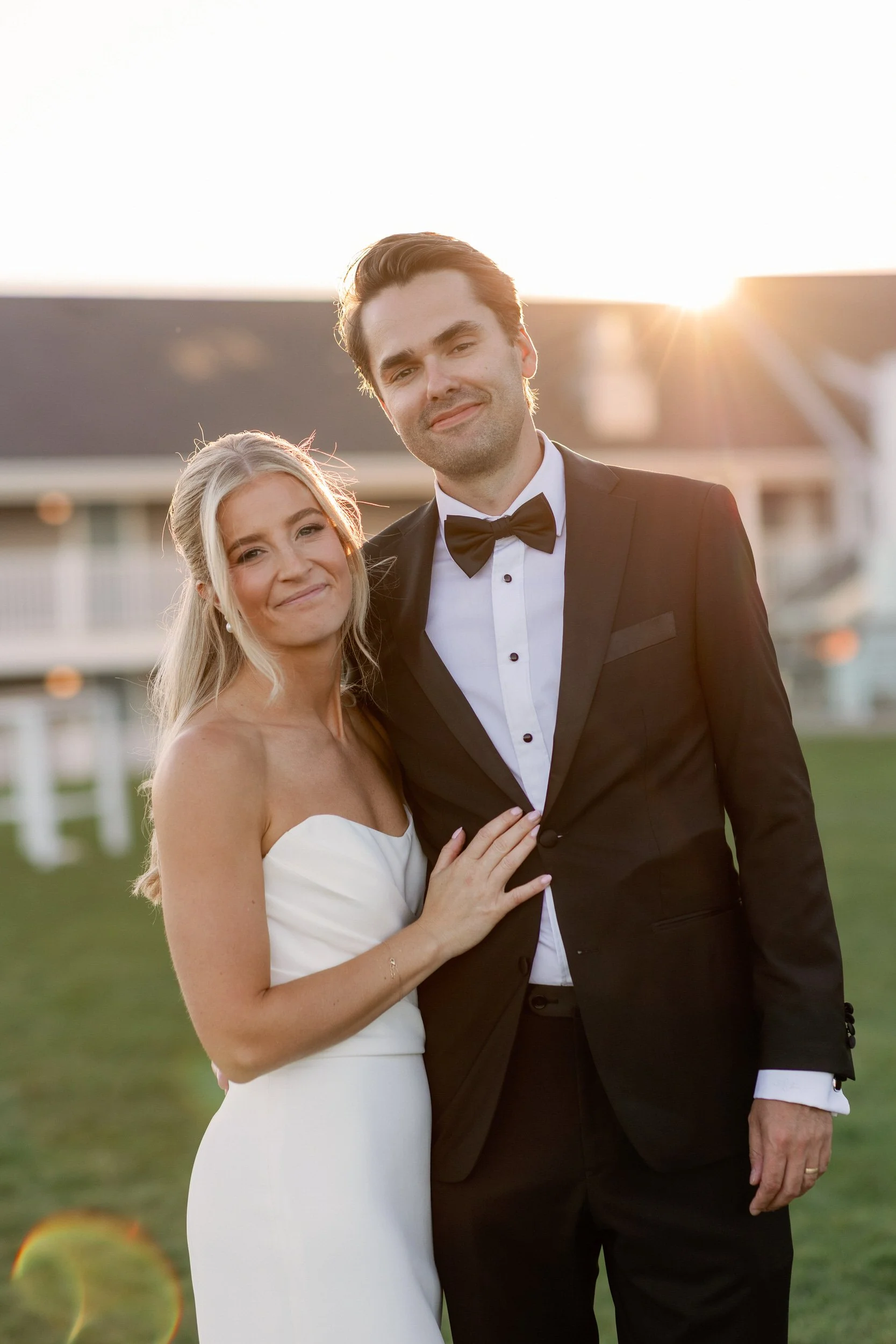 A newlywed couple with their arms around each other smiling