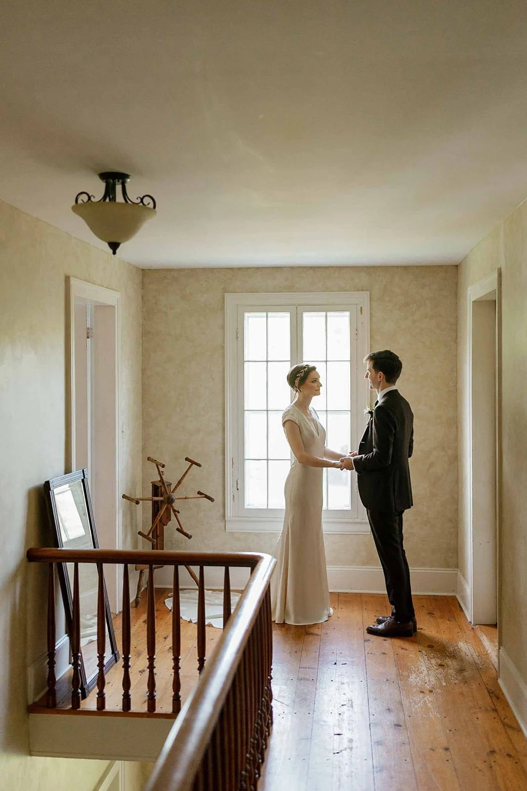 A newlywed couple holding hands and standing in a small hallway 