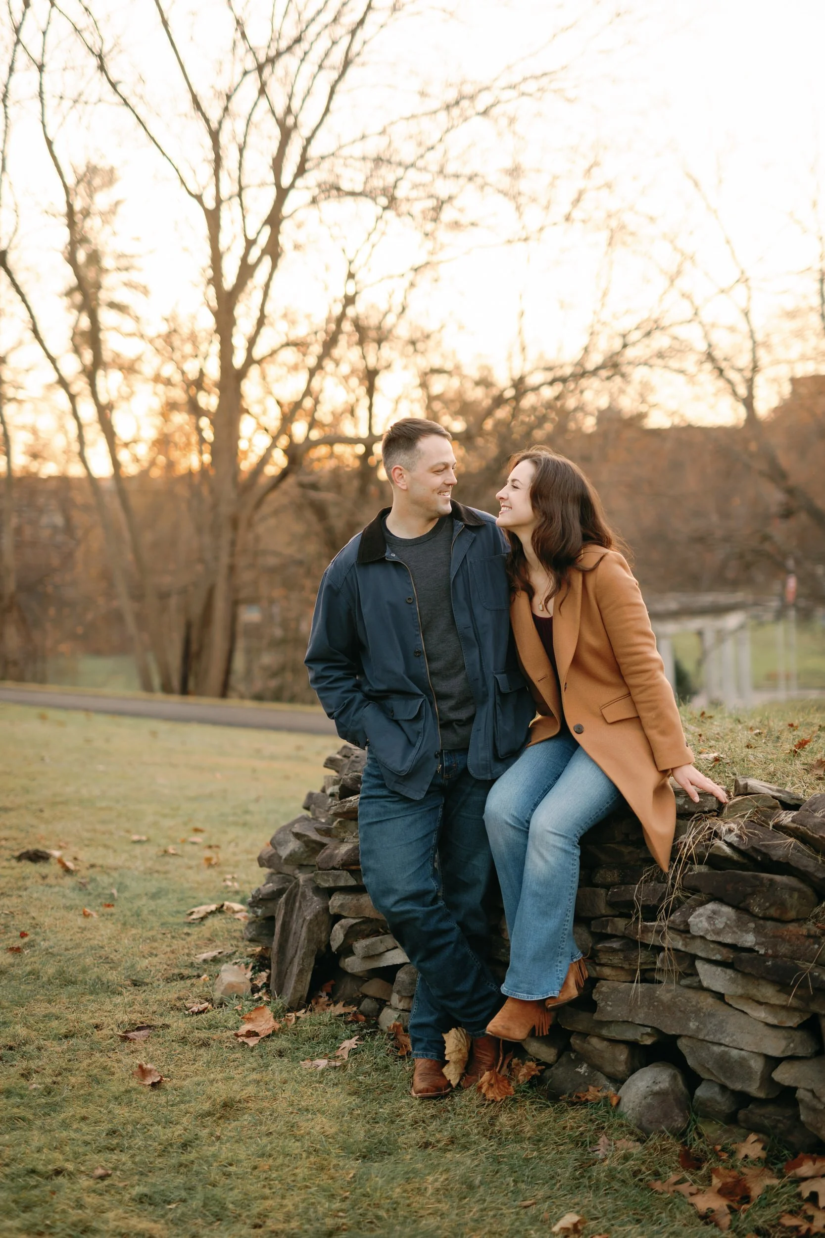 A couple sitting on a small stone wall laughing 