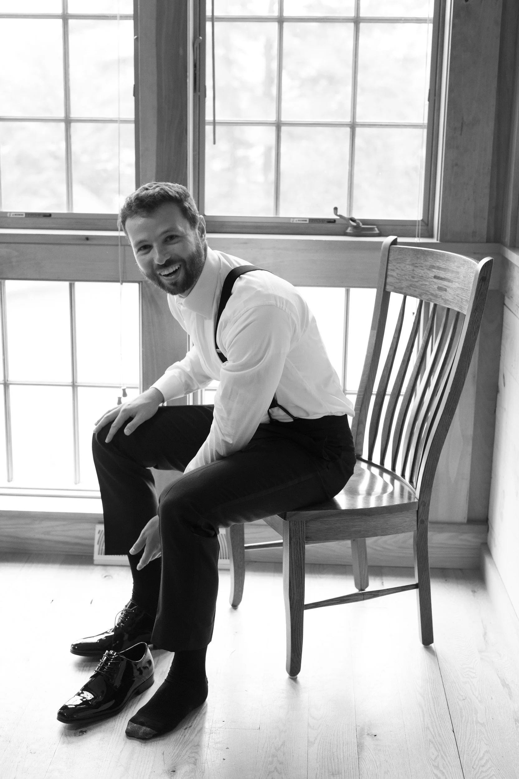 a person in a suit sitting in a chair as they smile and put on shoes 