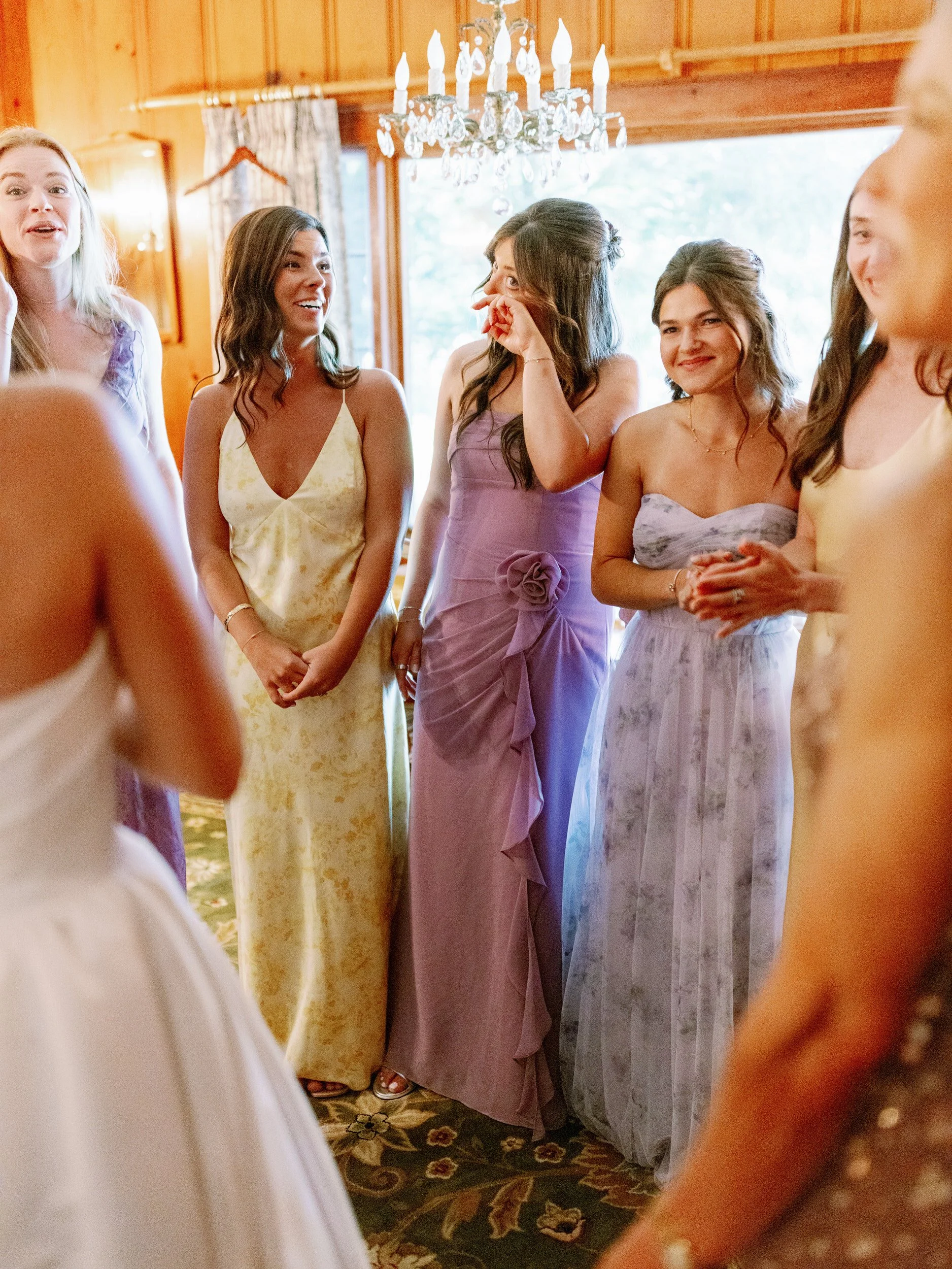 A wedding party standing around a newlywed and wiping away tears 