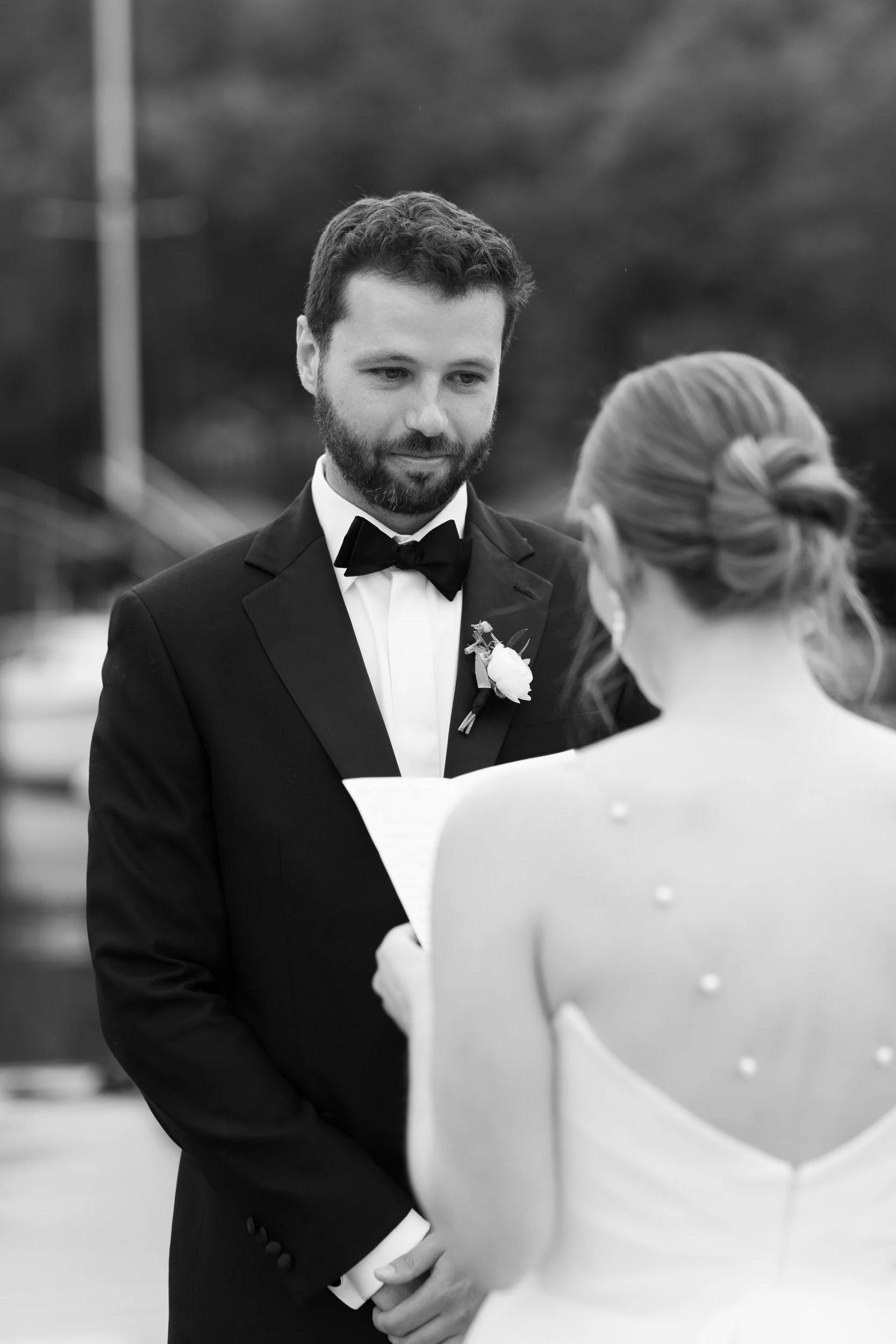 A person smiling at their partner as they read them their vows