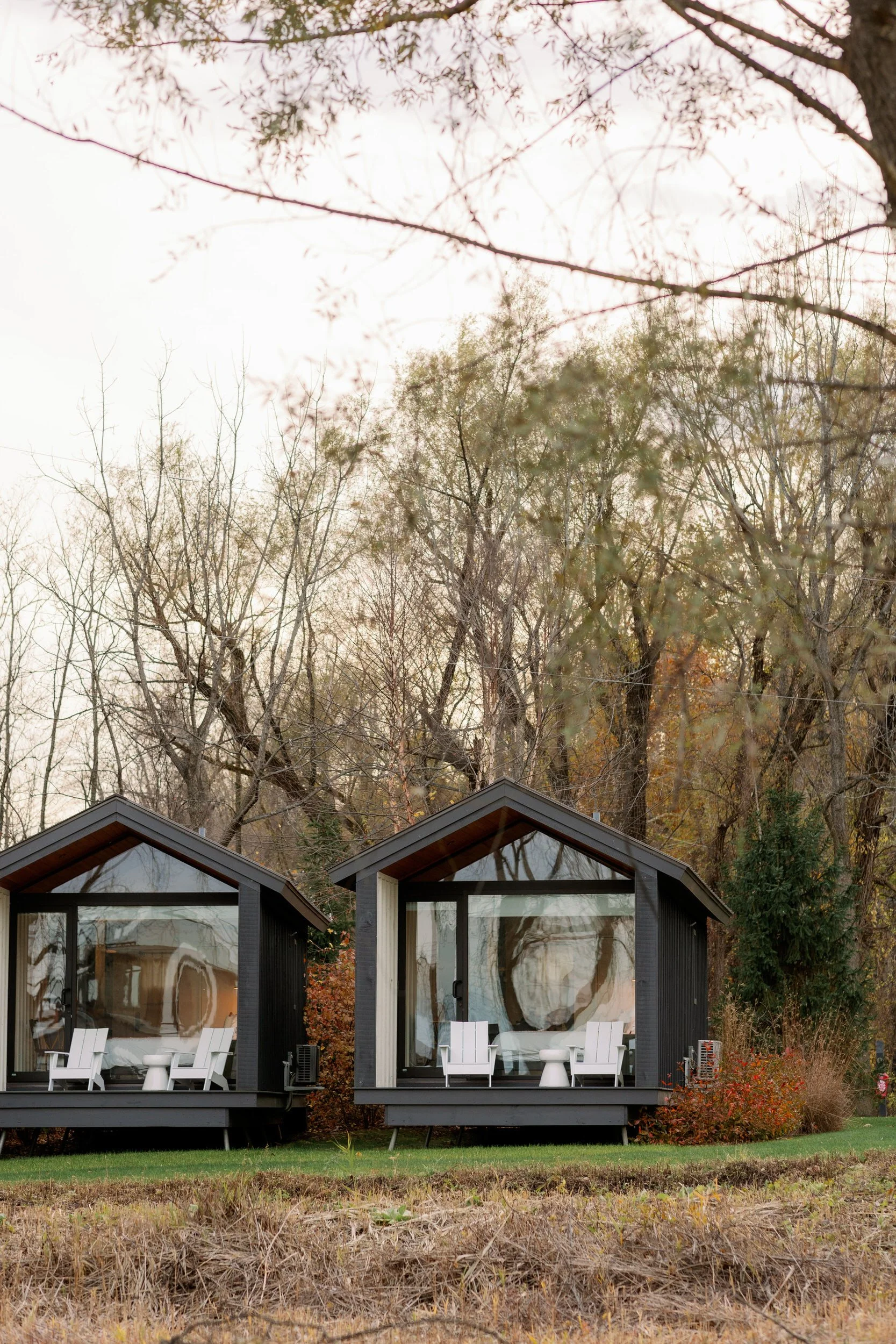 Two small black cabins situated next to each other in a wooded area