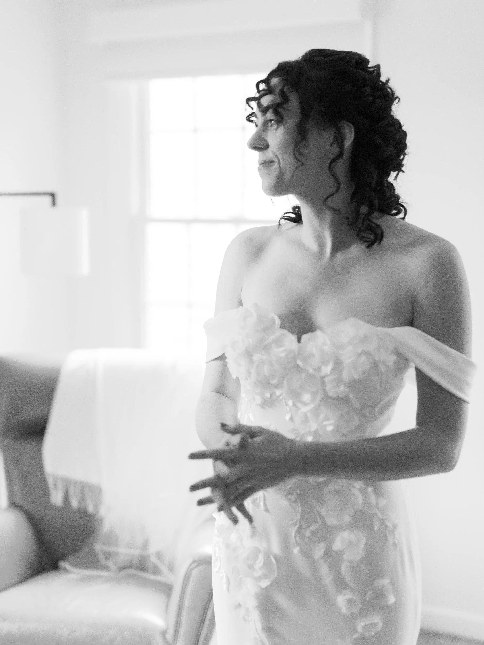 A person in a wedding dress smiling and looking off to the side 