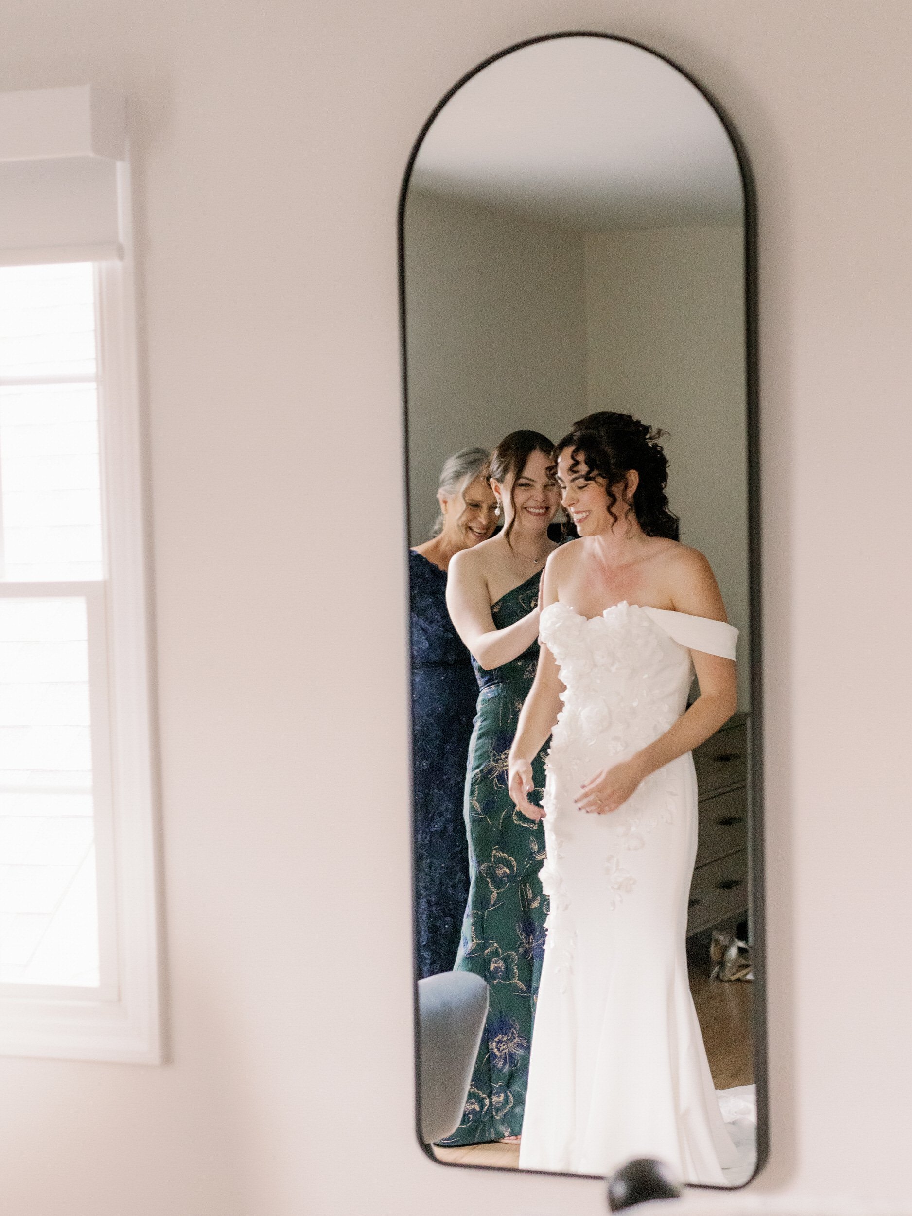 A person helping someone put on a wedding dress 