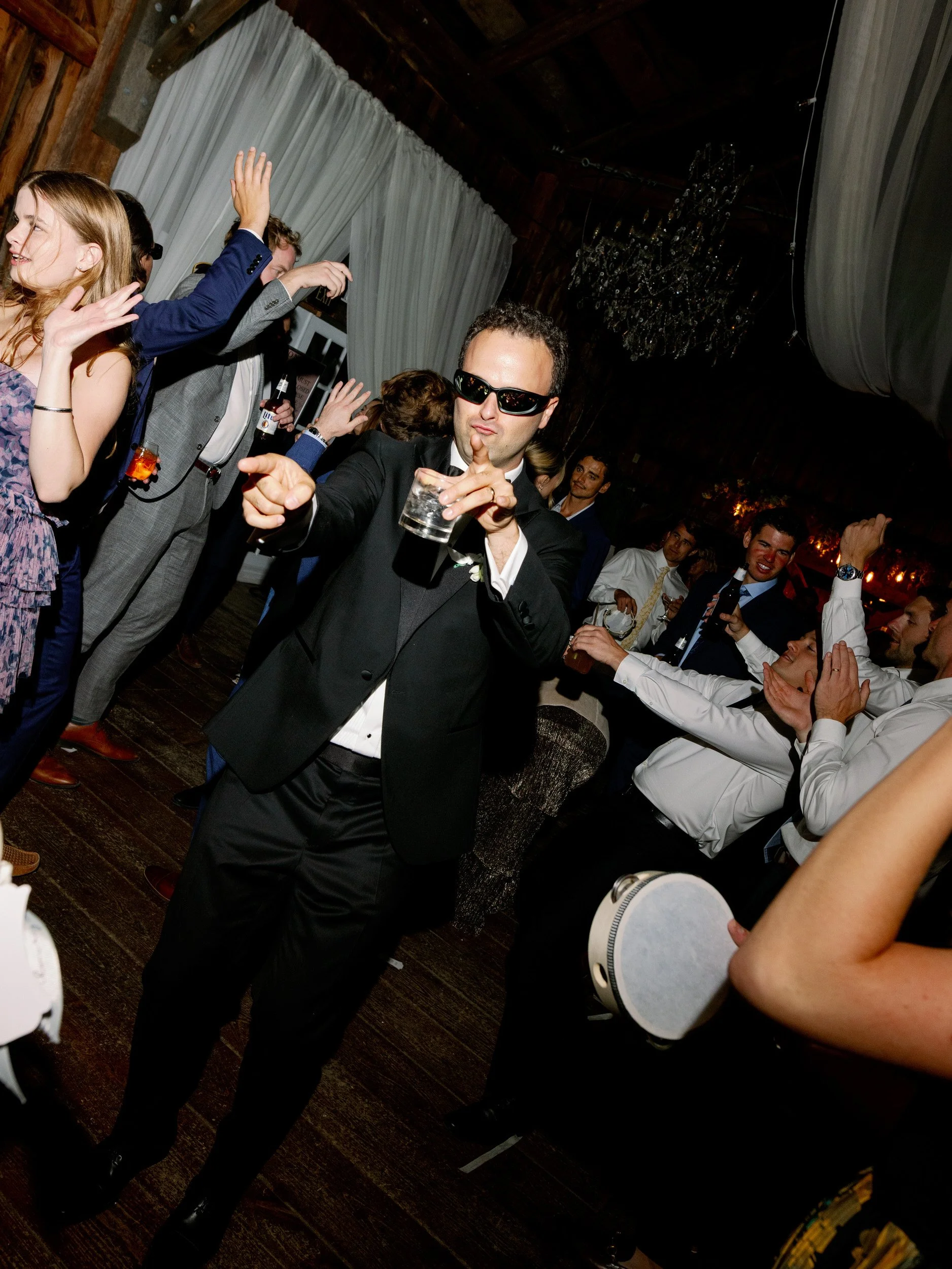 Wedding guests dancing in sunglasses during a reception 