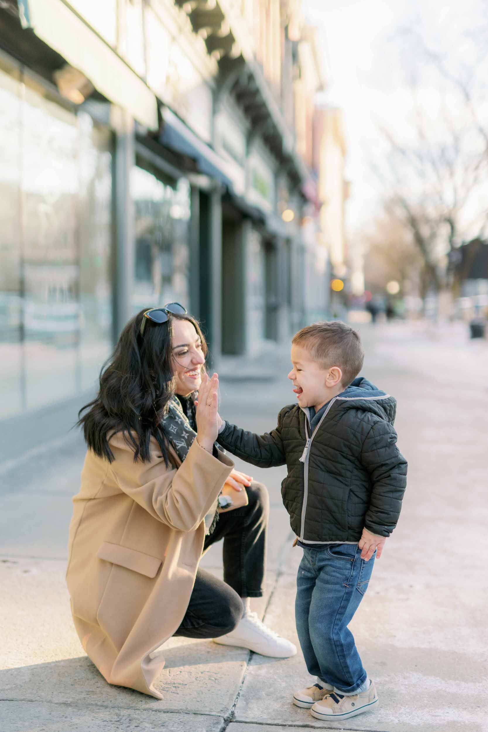 A parent kneeling down and giving their child a high five