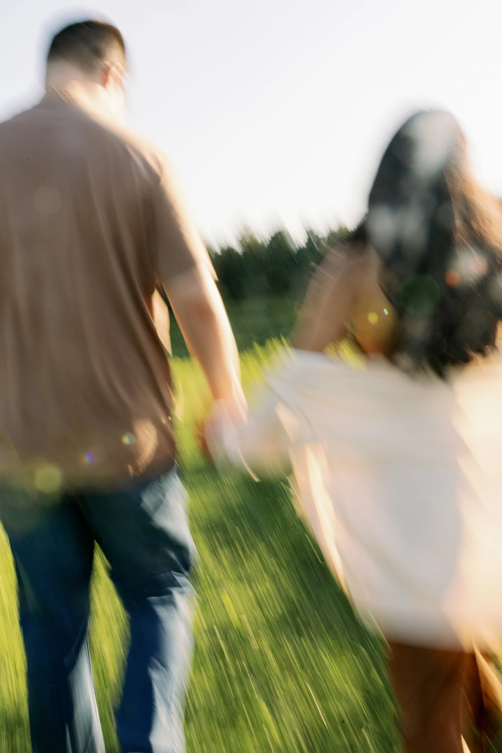 A couple holding hands and running in a field 