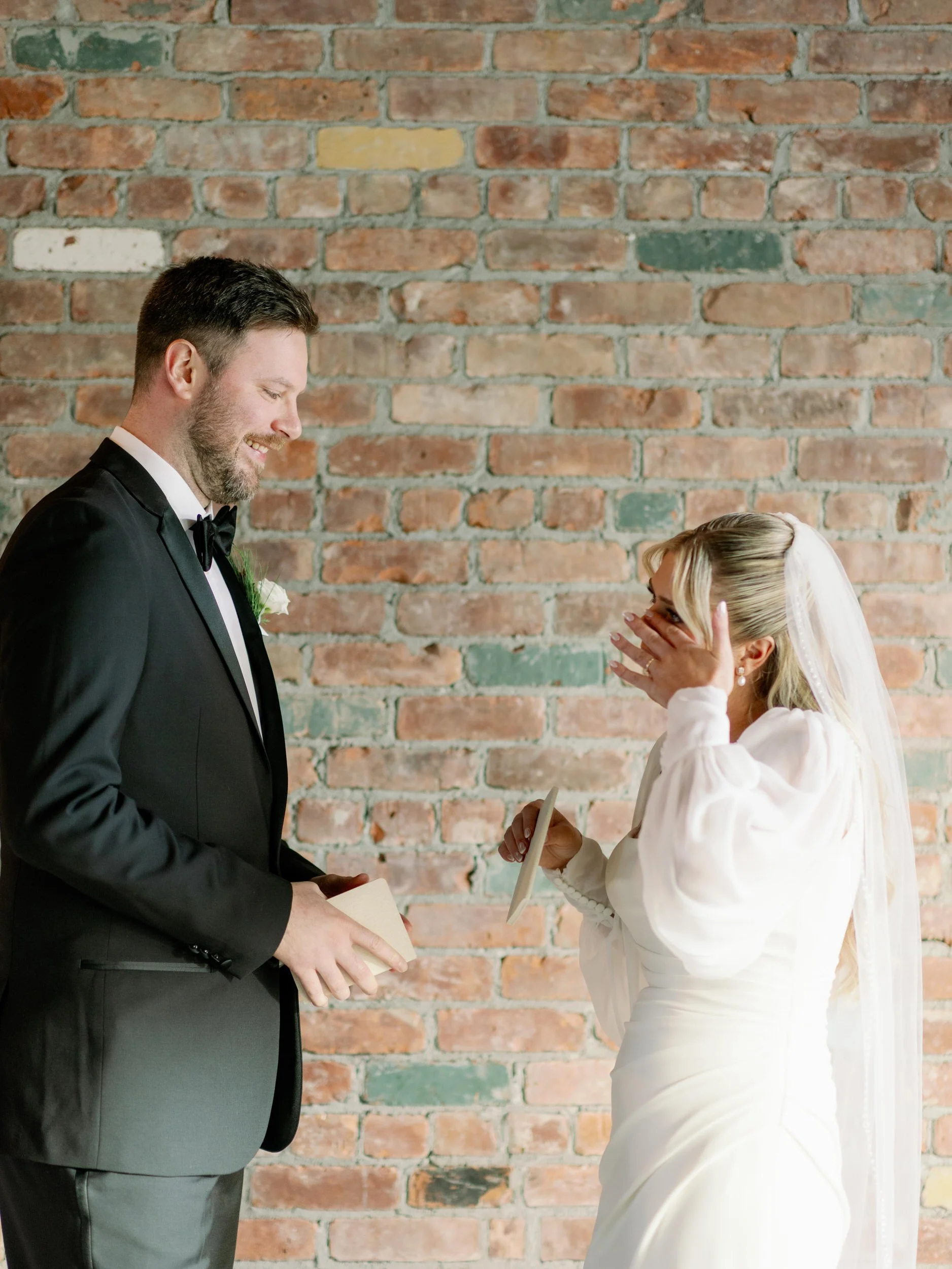 A newlywed wiping a tear as they exchange notes with their partner