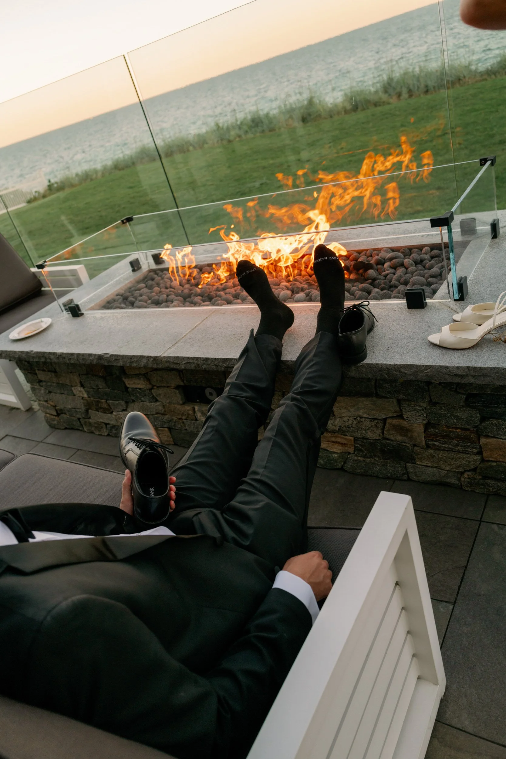 A person with their feet rested on an outdoor fireplace 