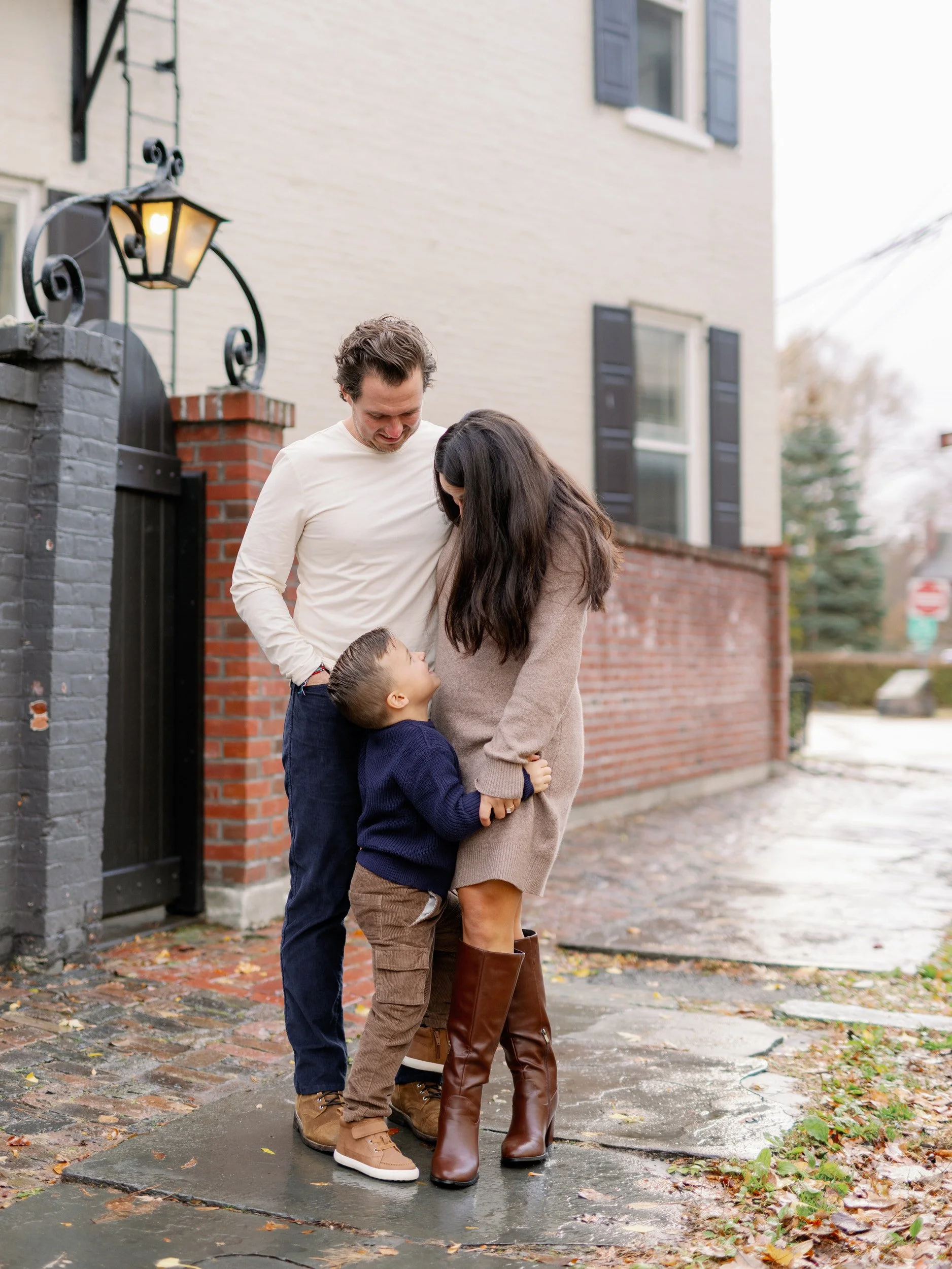 Two parents looking down at their child standing in front of them 