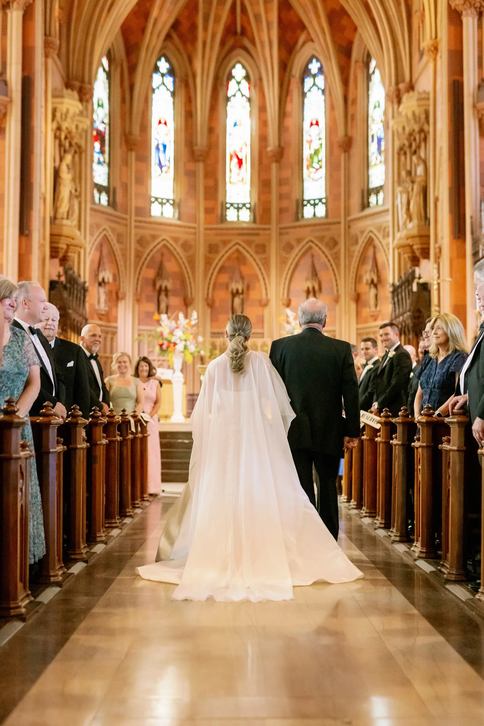A person in a wedding dress being walked down the aisle in a church 