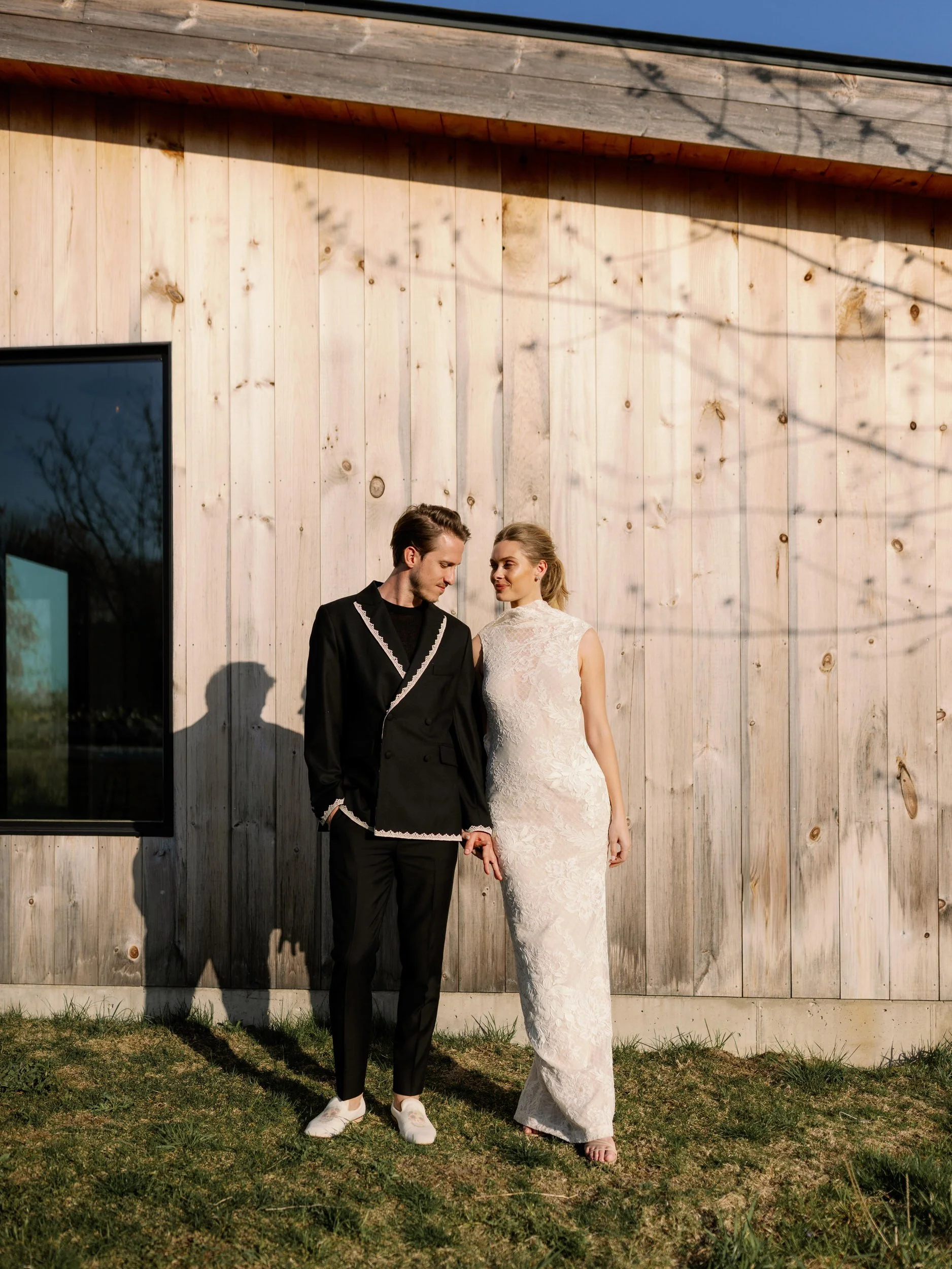 Newlyweds holding hands outside of a modern barn