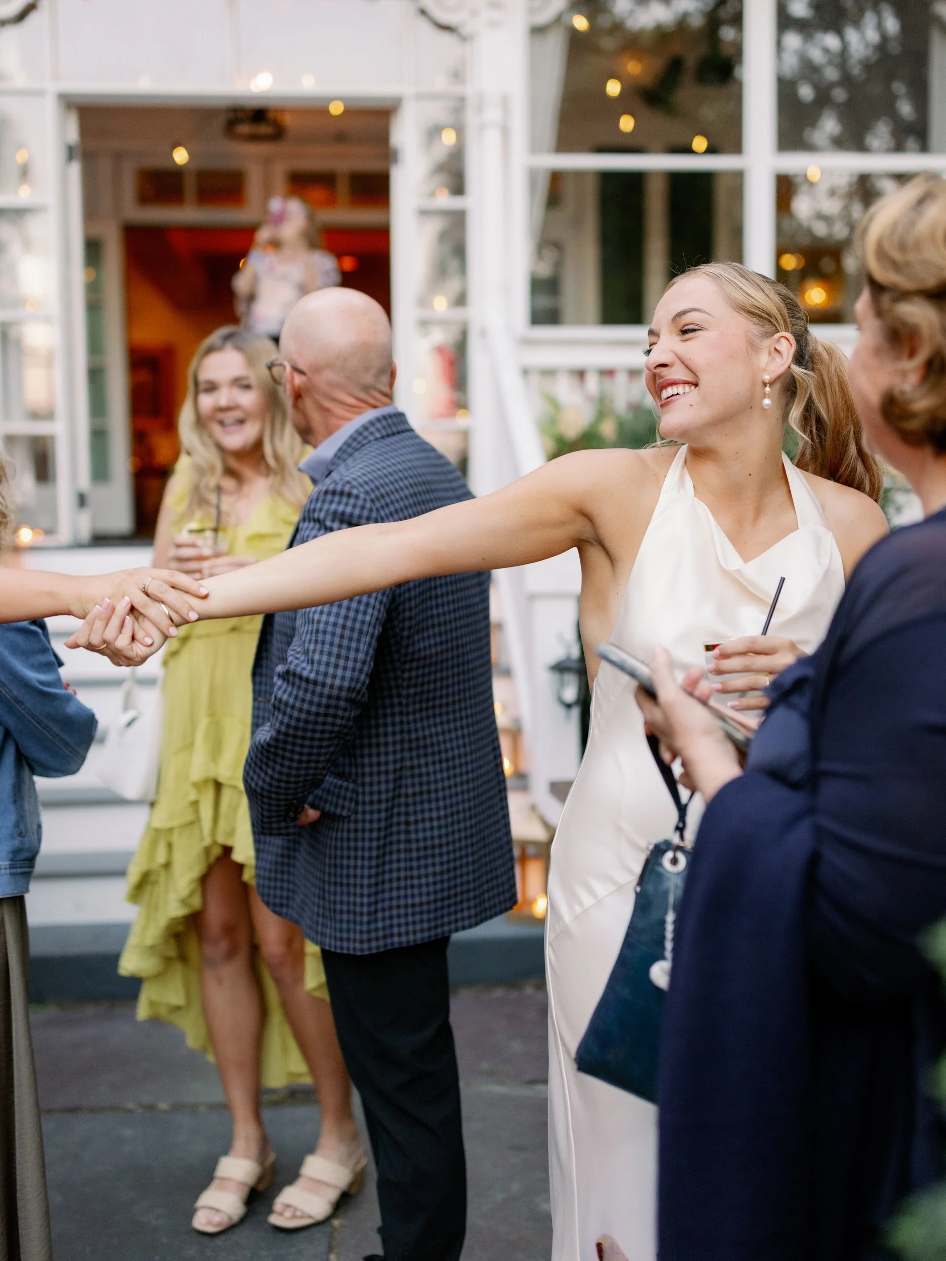 A newlywed smiling as they reach out to hold hands with a guest 