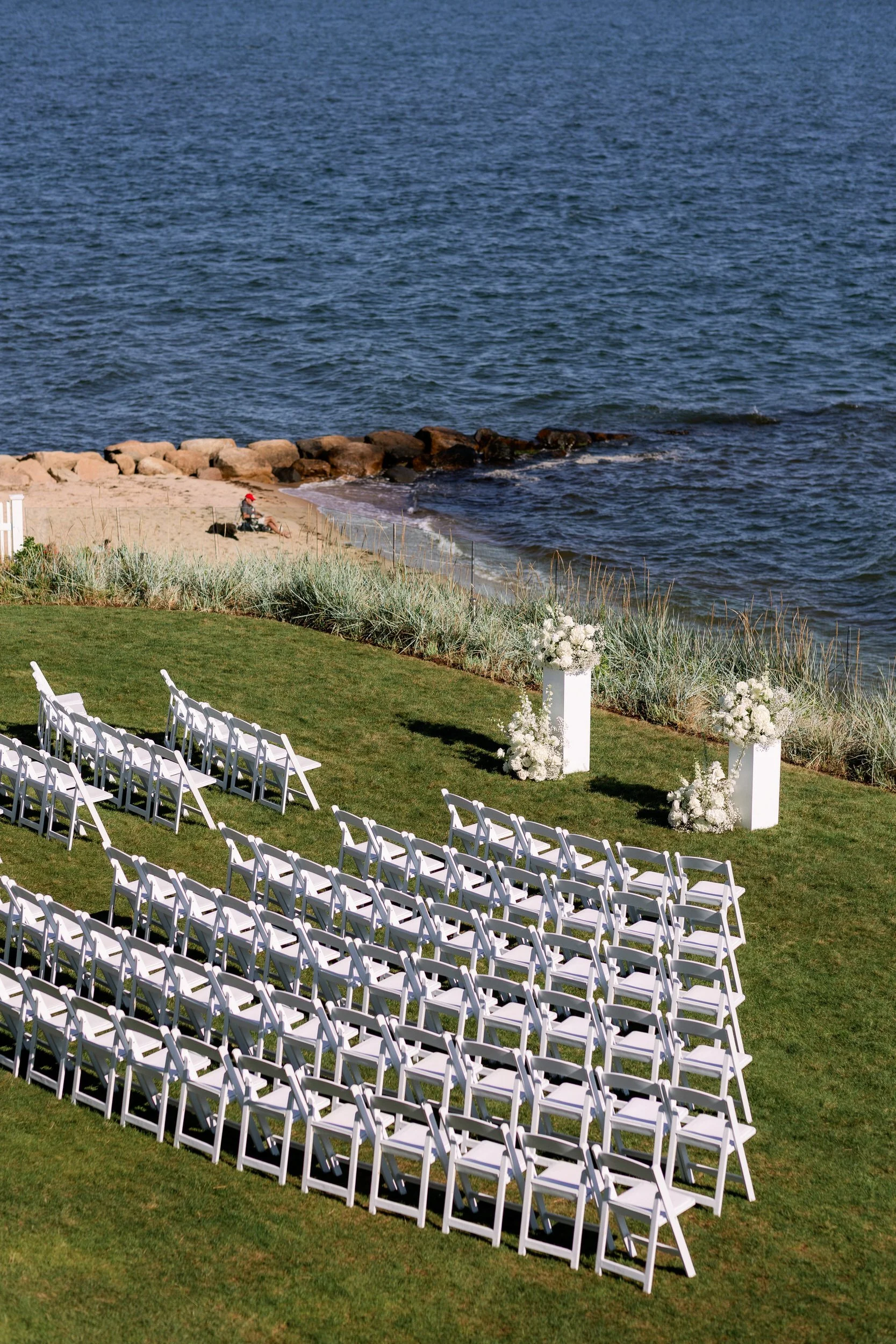 An aerial view of a wedding ceremony set up on the edge of the water 