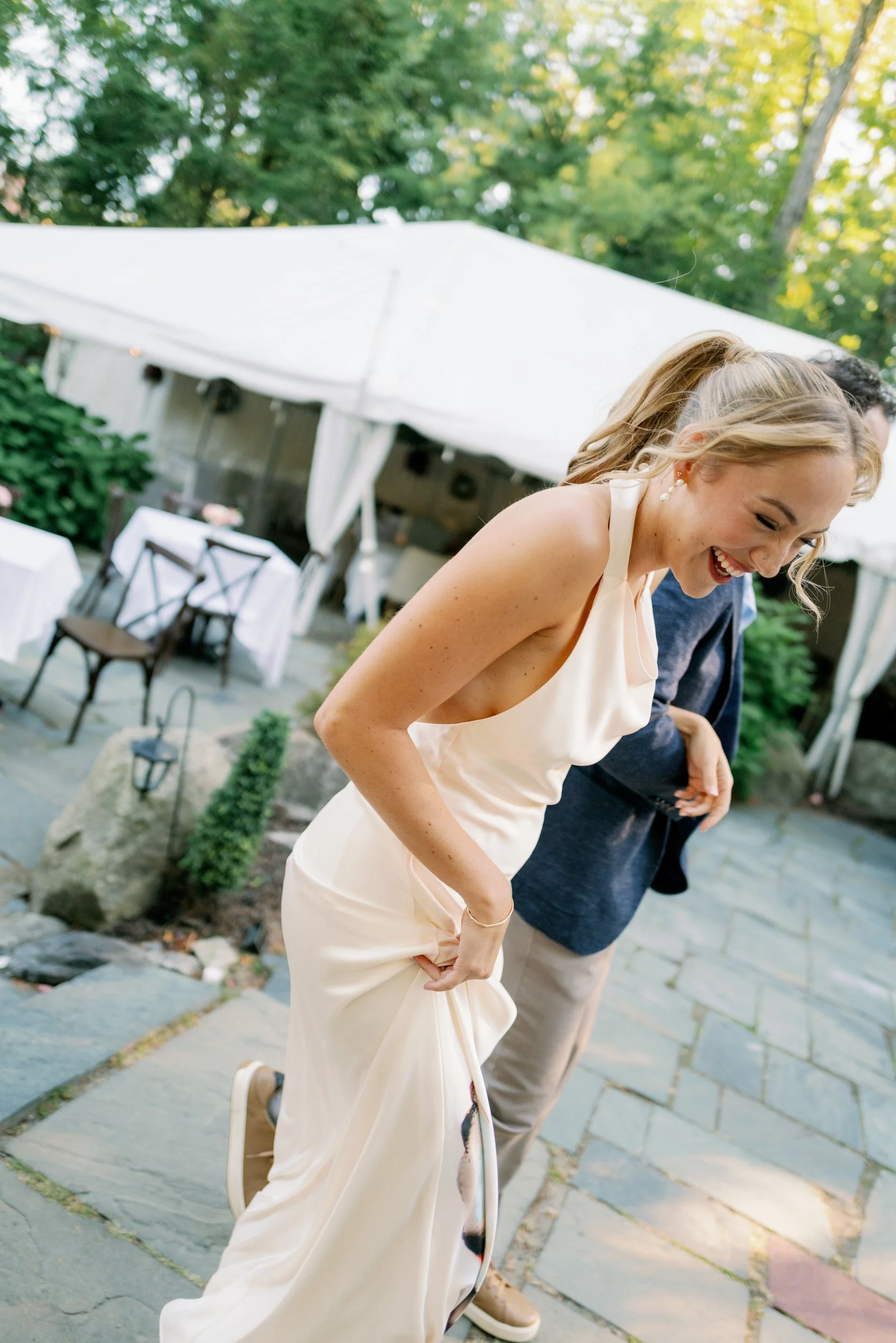 A newlywed laughing as they walk on a patio 