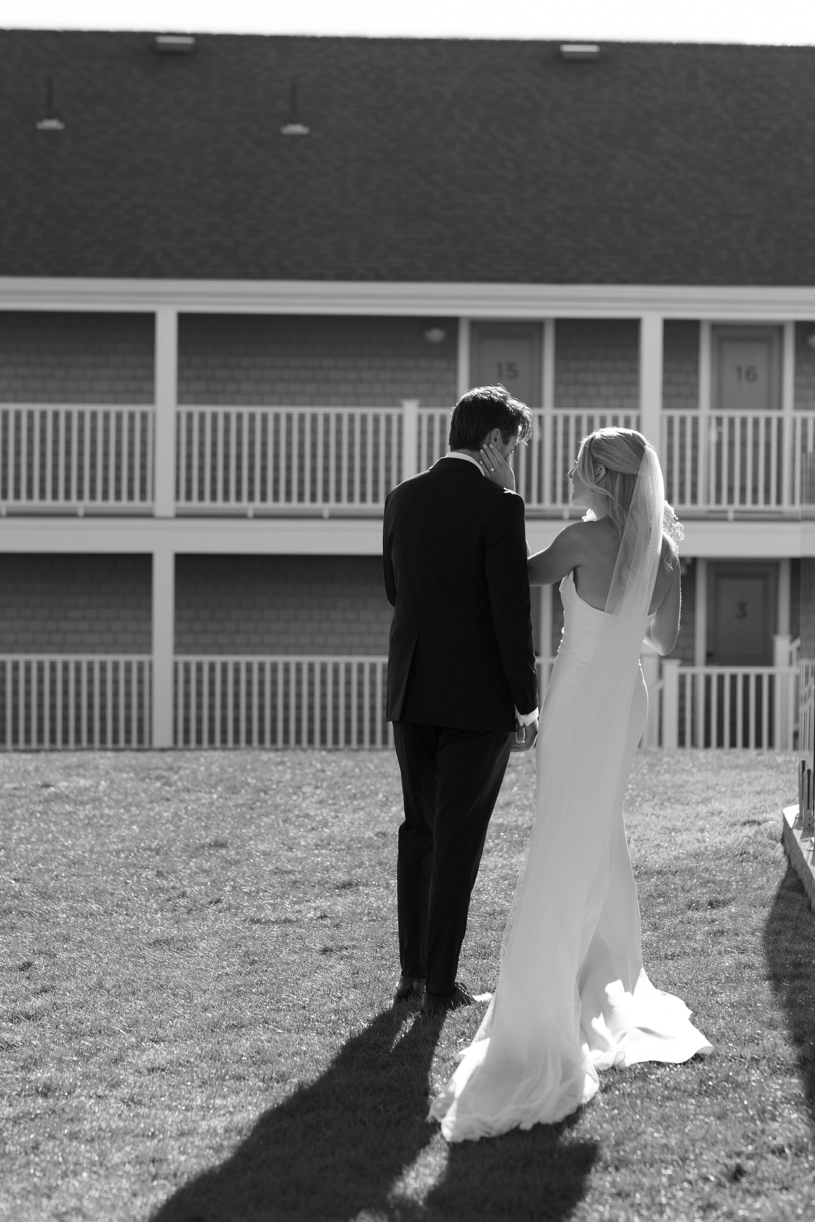 Newlyweds standing close and talking together while standing out on a lawn 