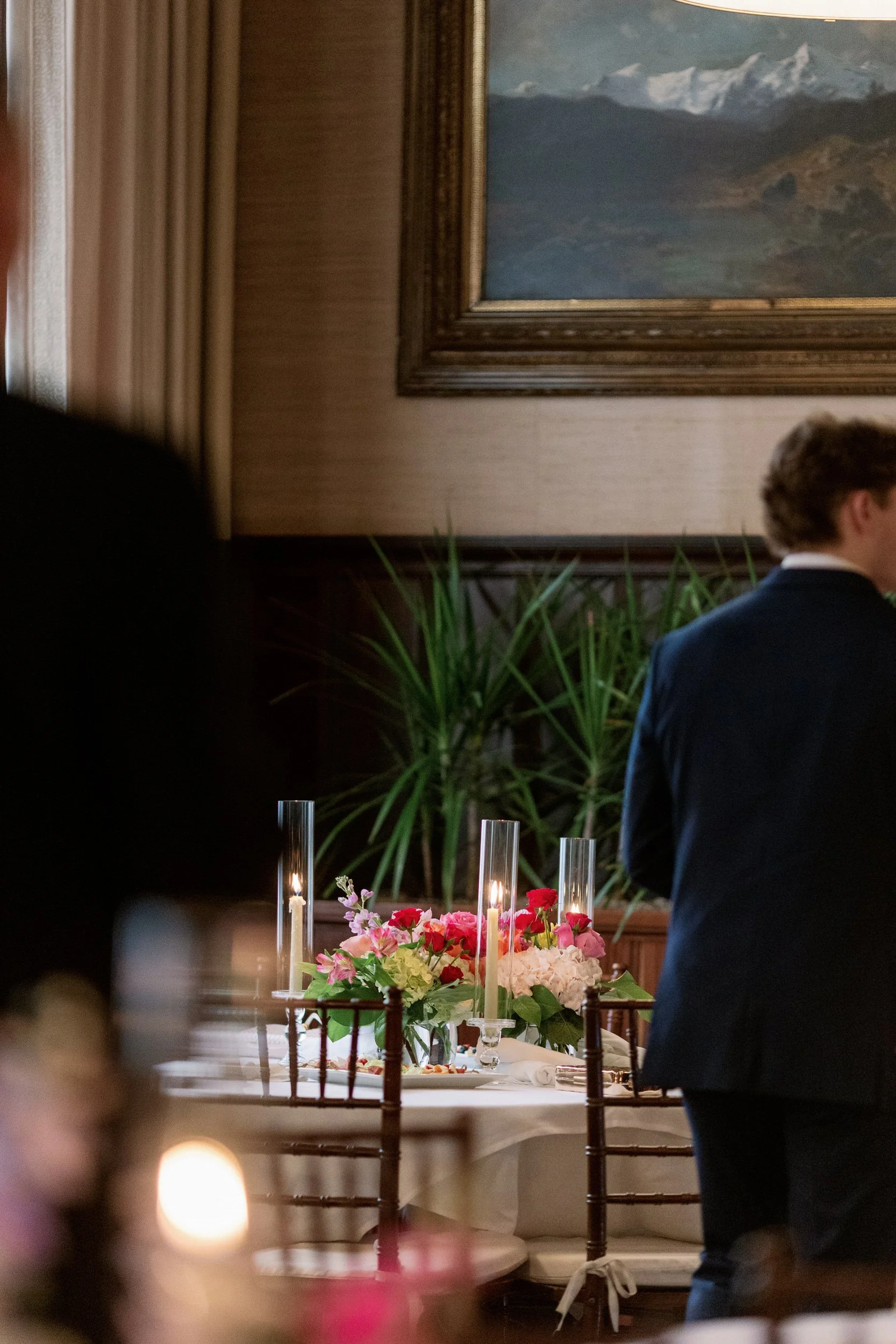 Wedding guests standing around tables with pink floral arrangements 