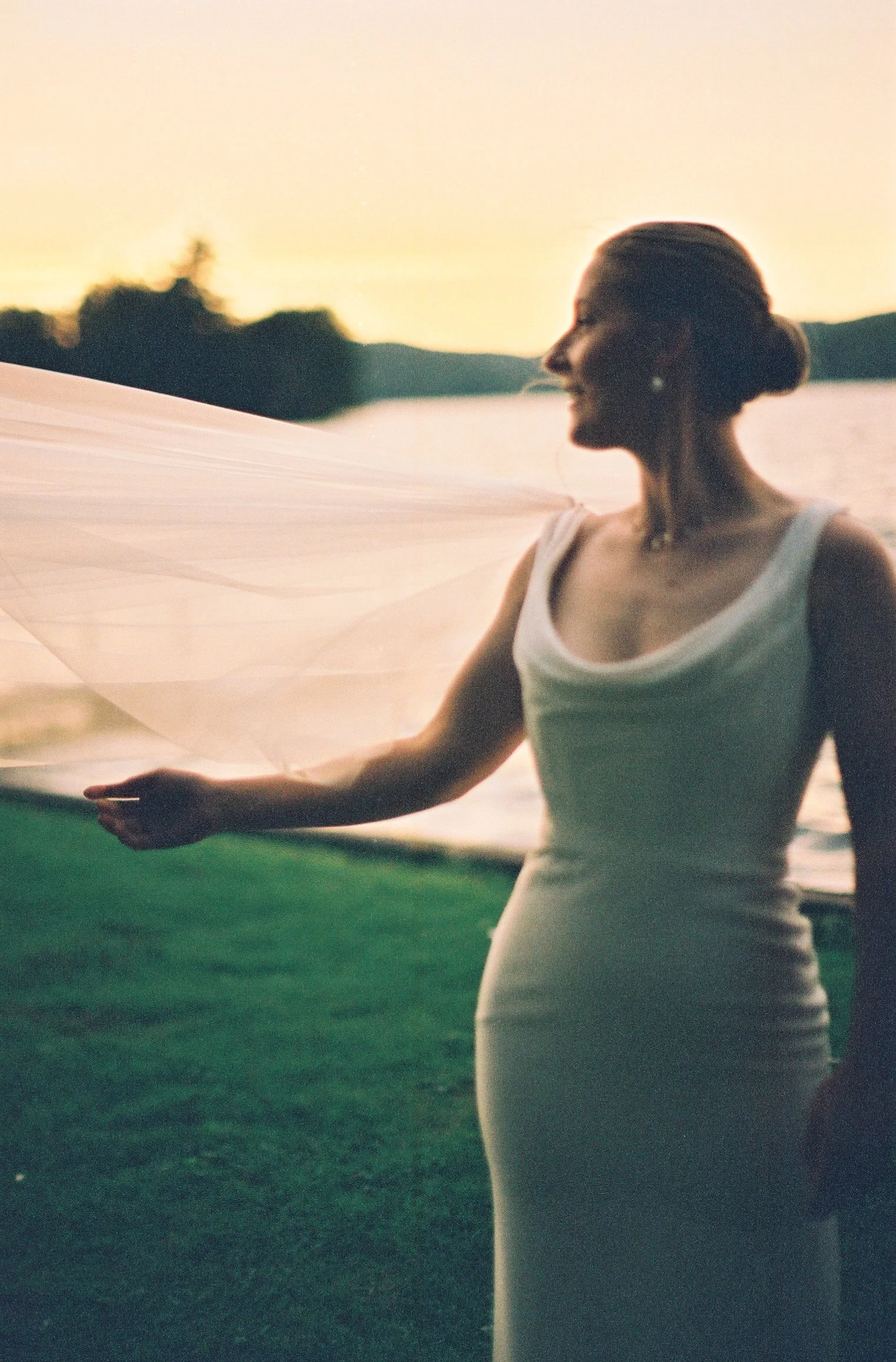 A person in a wedding dress looking off to the side as their veil flows in the wind