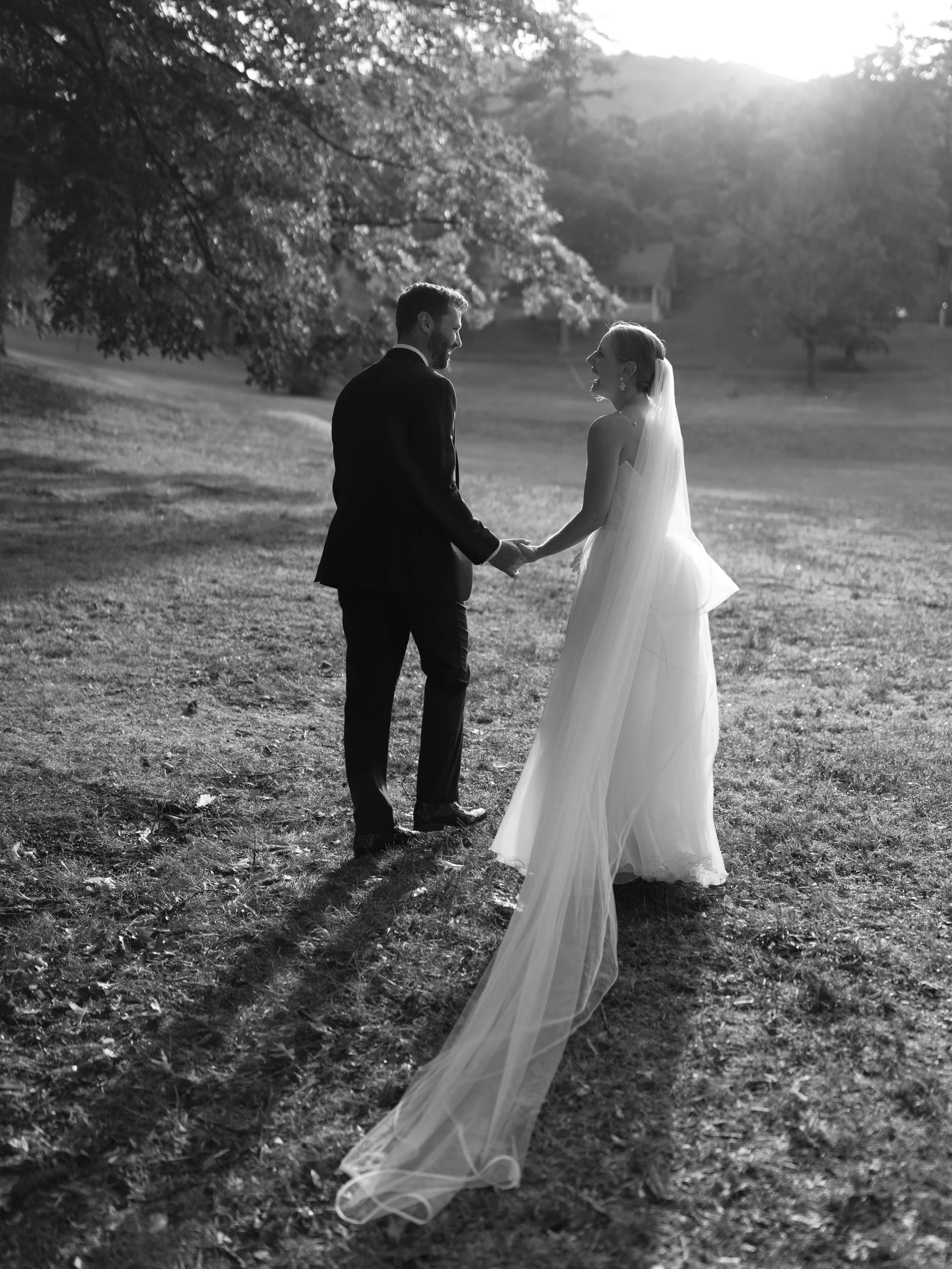 Newlyweds holding hands and walking in a field 