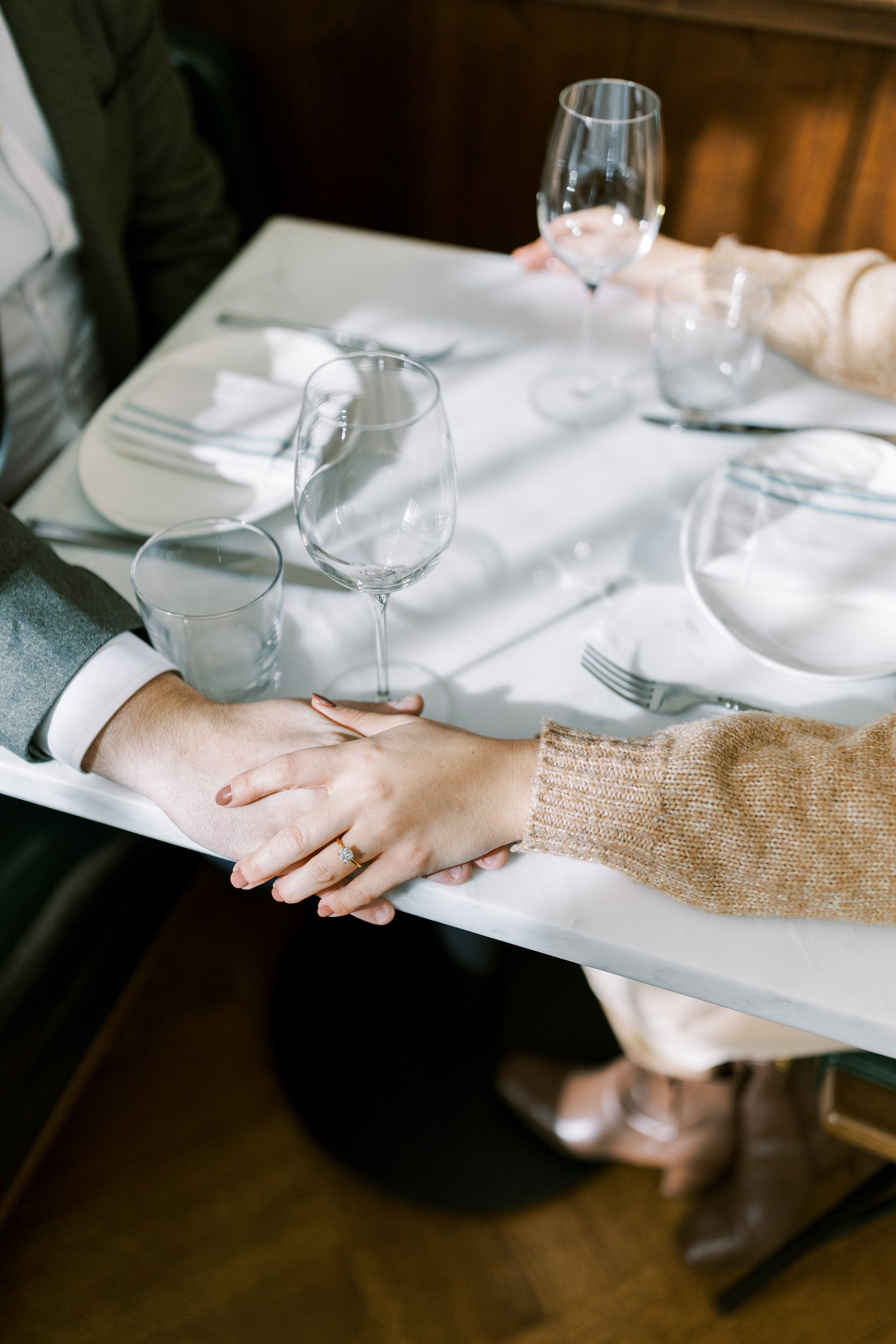 A close up of a couple holding hands on a table