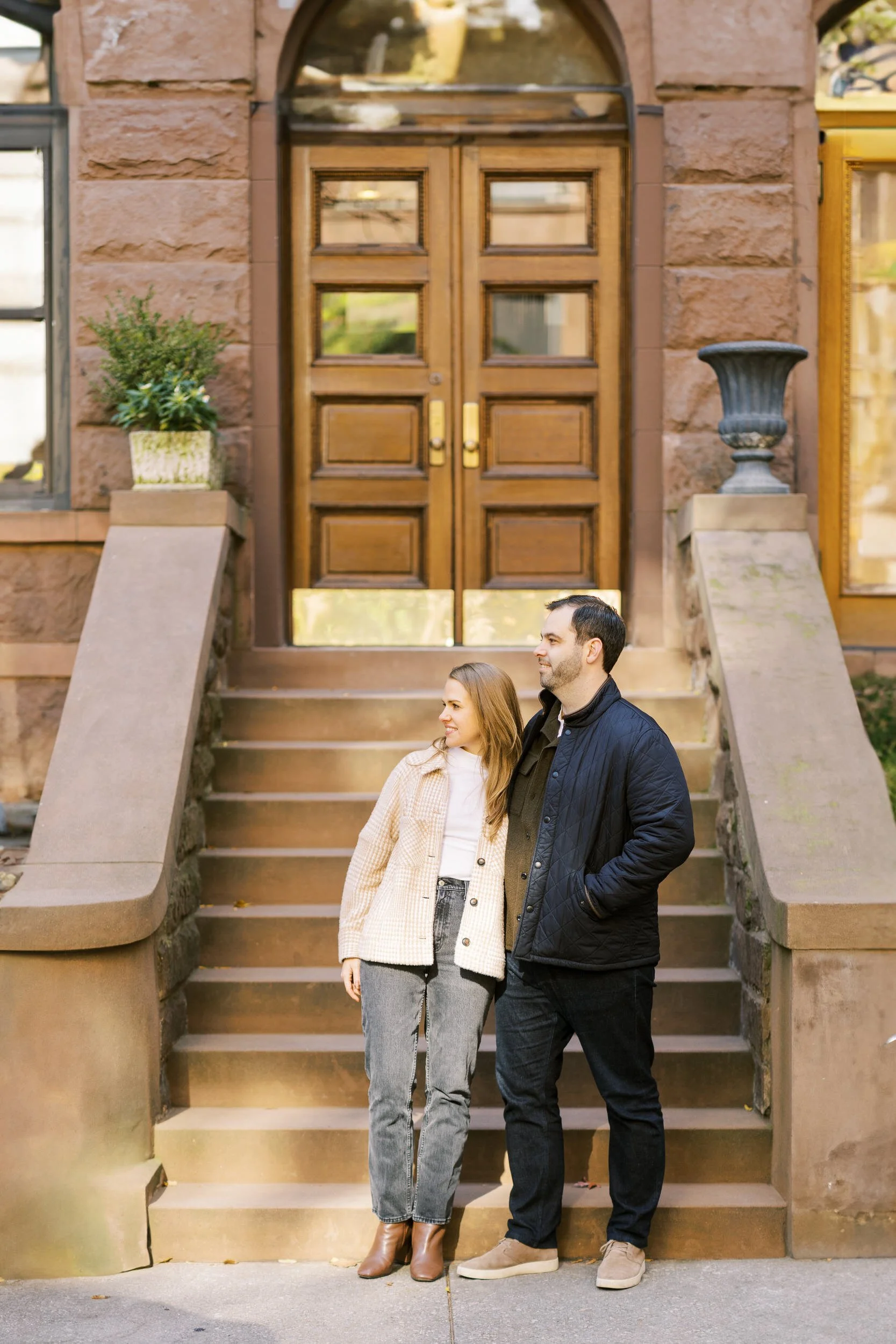 A couple standing at the bottom of a short staircase leading to a townhouse