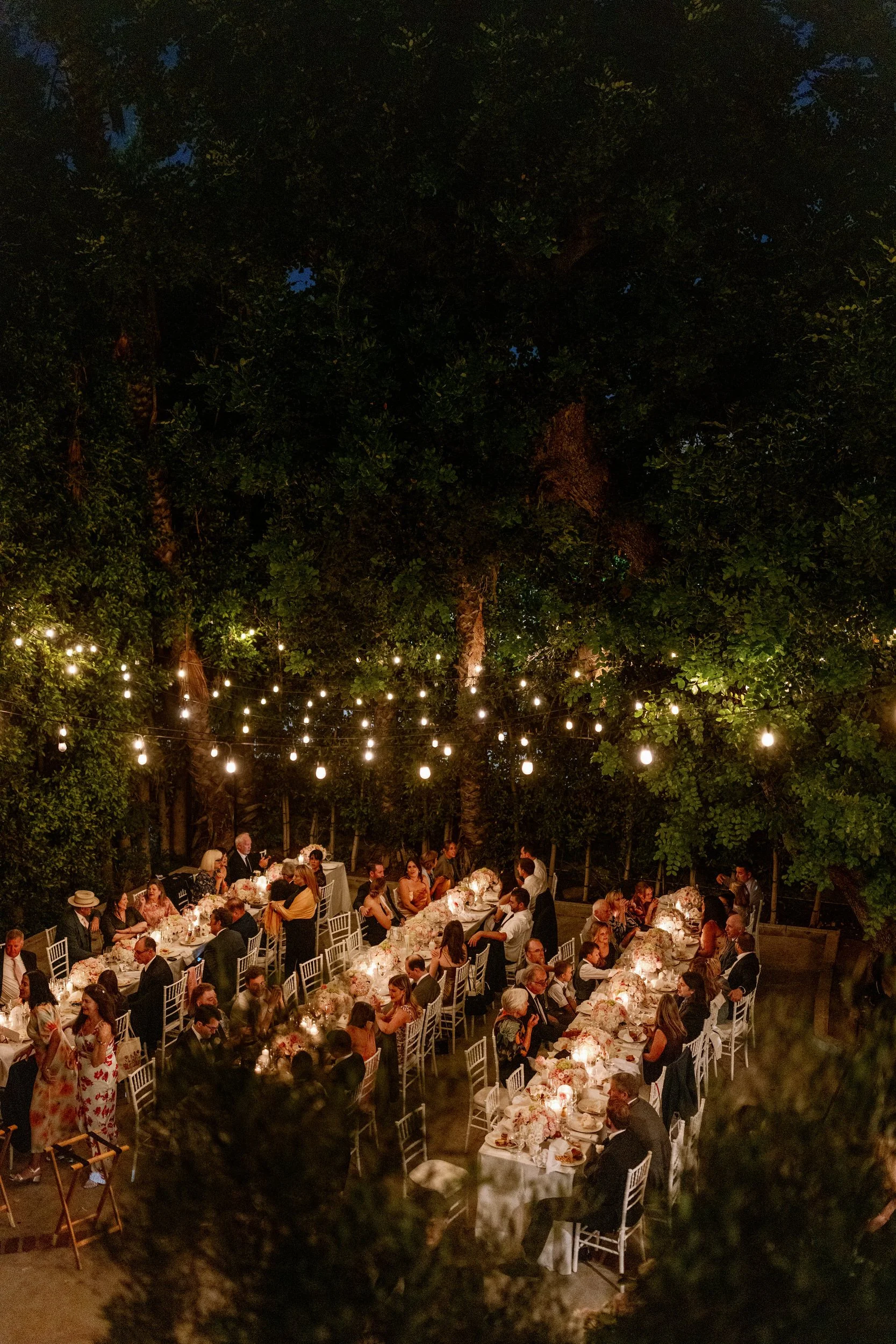 Wedding guests sitting at long rectangular tables during an outdoor wedding reception 