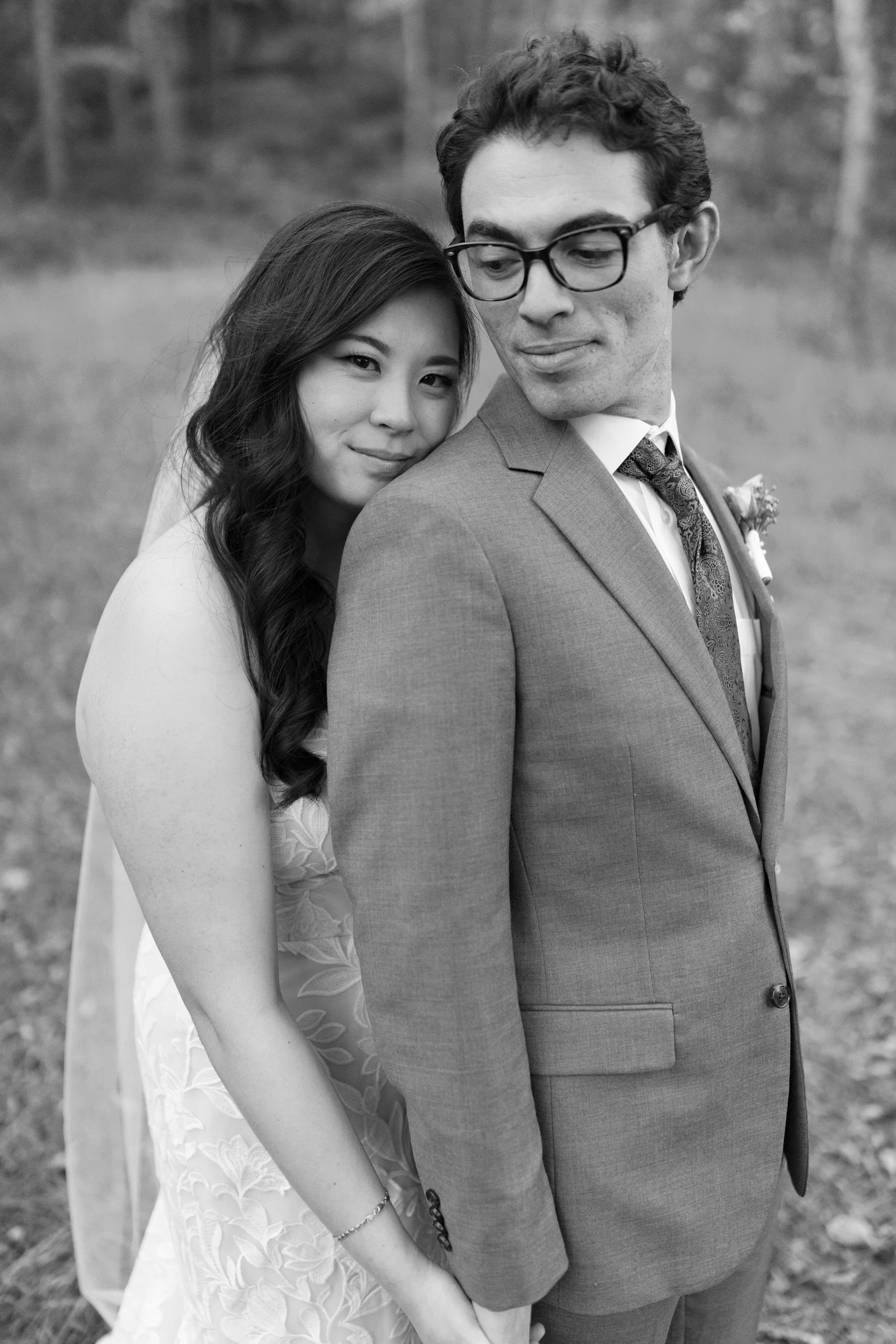Newlyweds standing on in front of the other as they lean into each other 