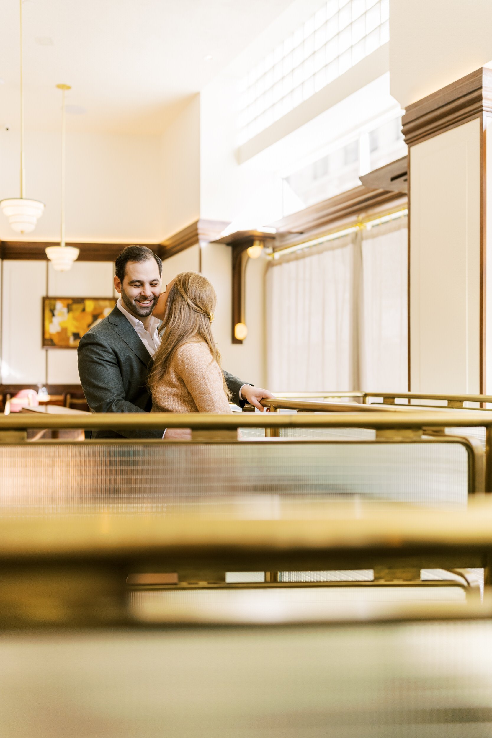 A person kissing their partner's cheek as they stand in an empty restaurant