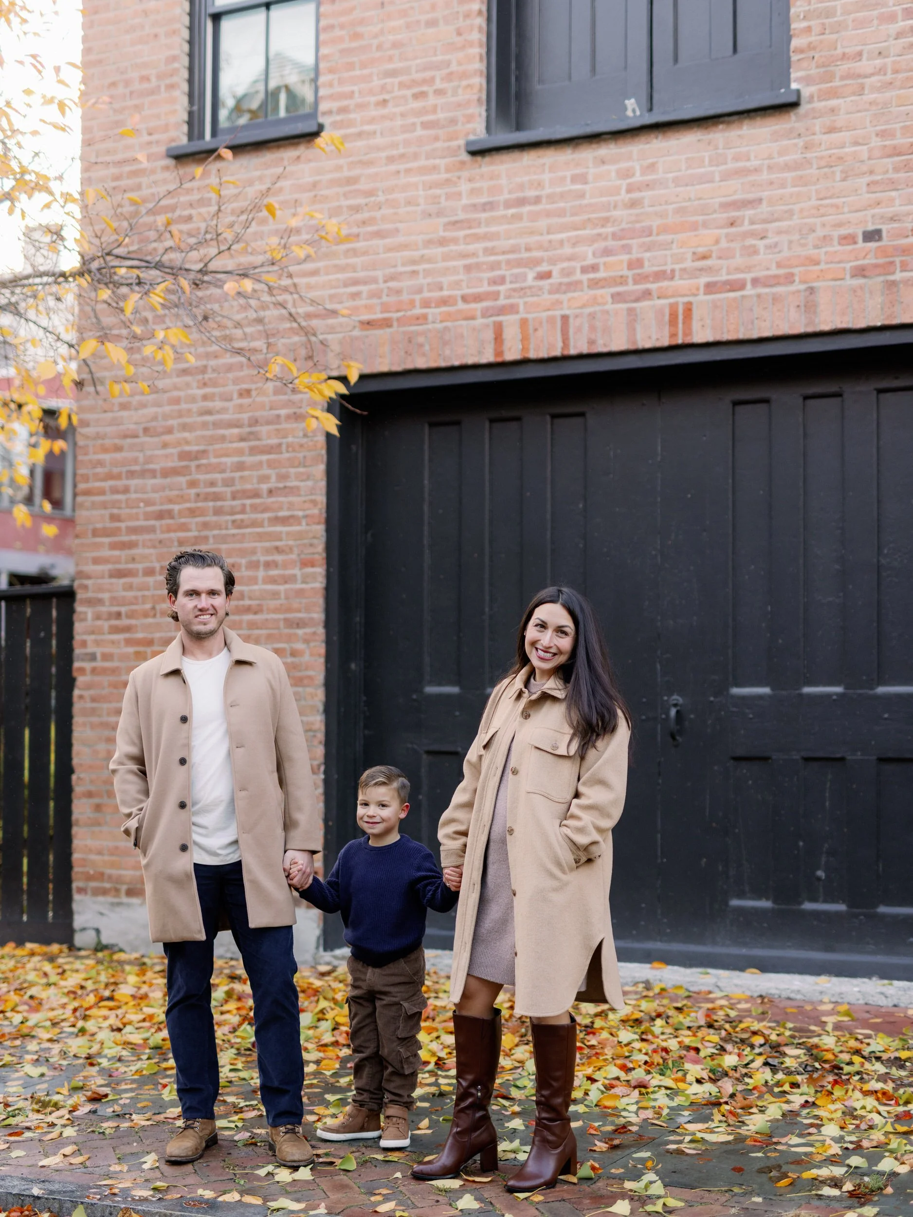 Parents standing on either side of their child holding their hands 