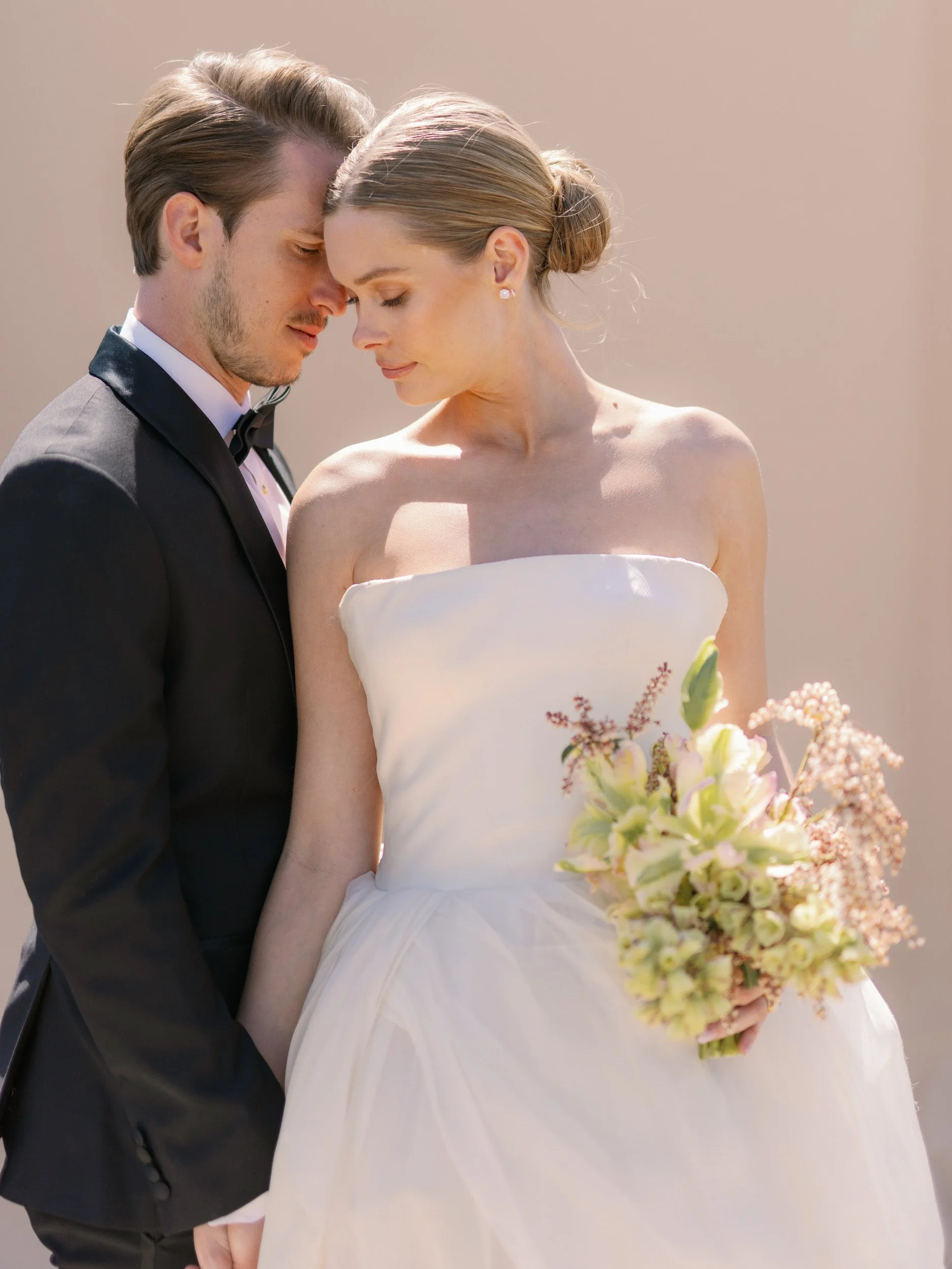 Newlyweds holding hands and resting their heads together 