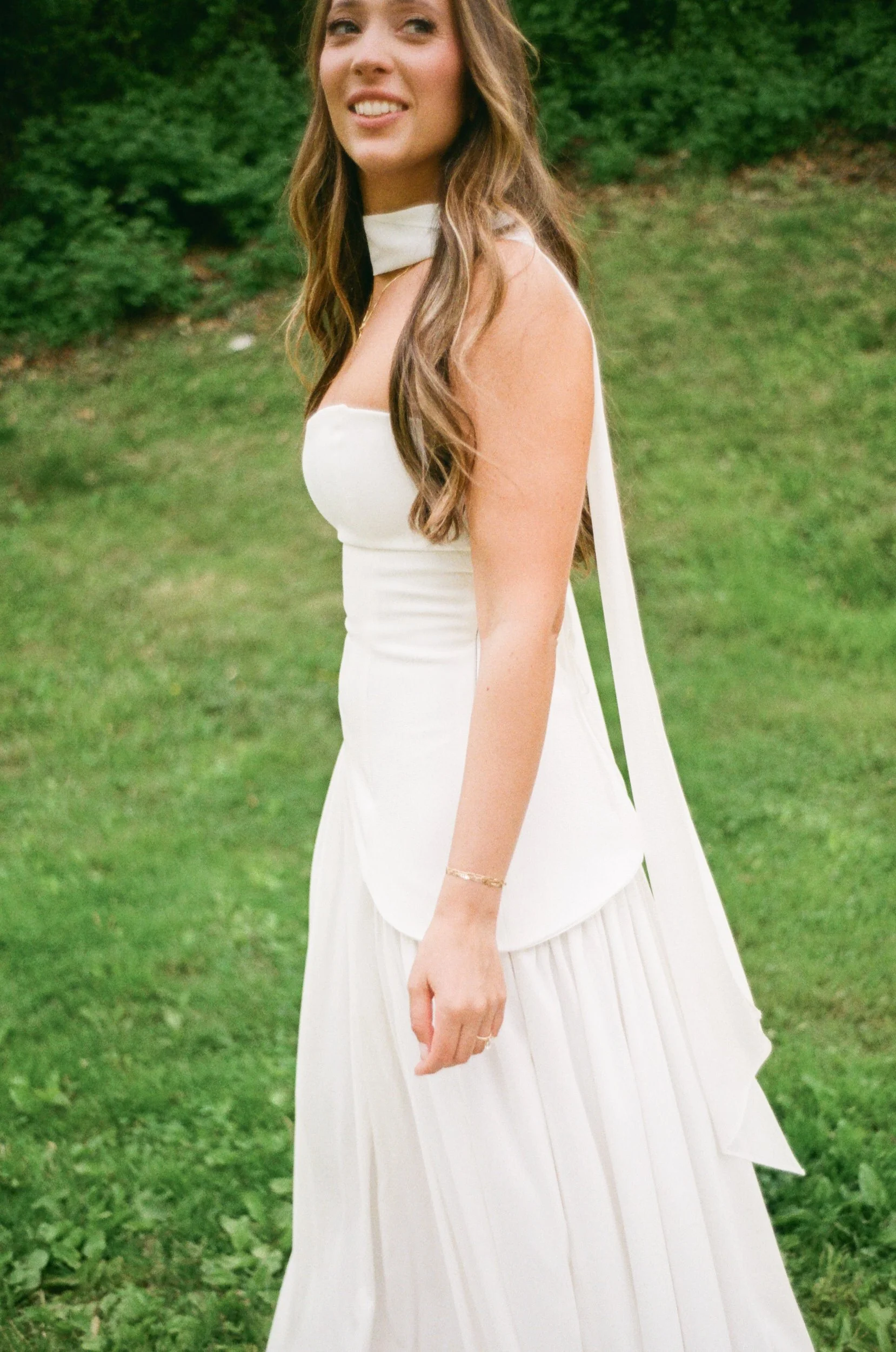 A person in a wedding dress smiling in a field 
