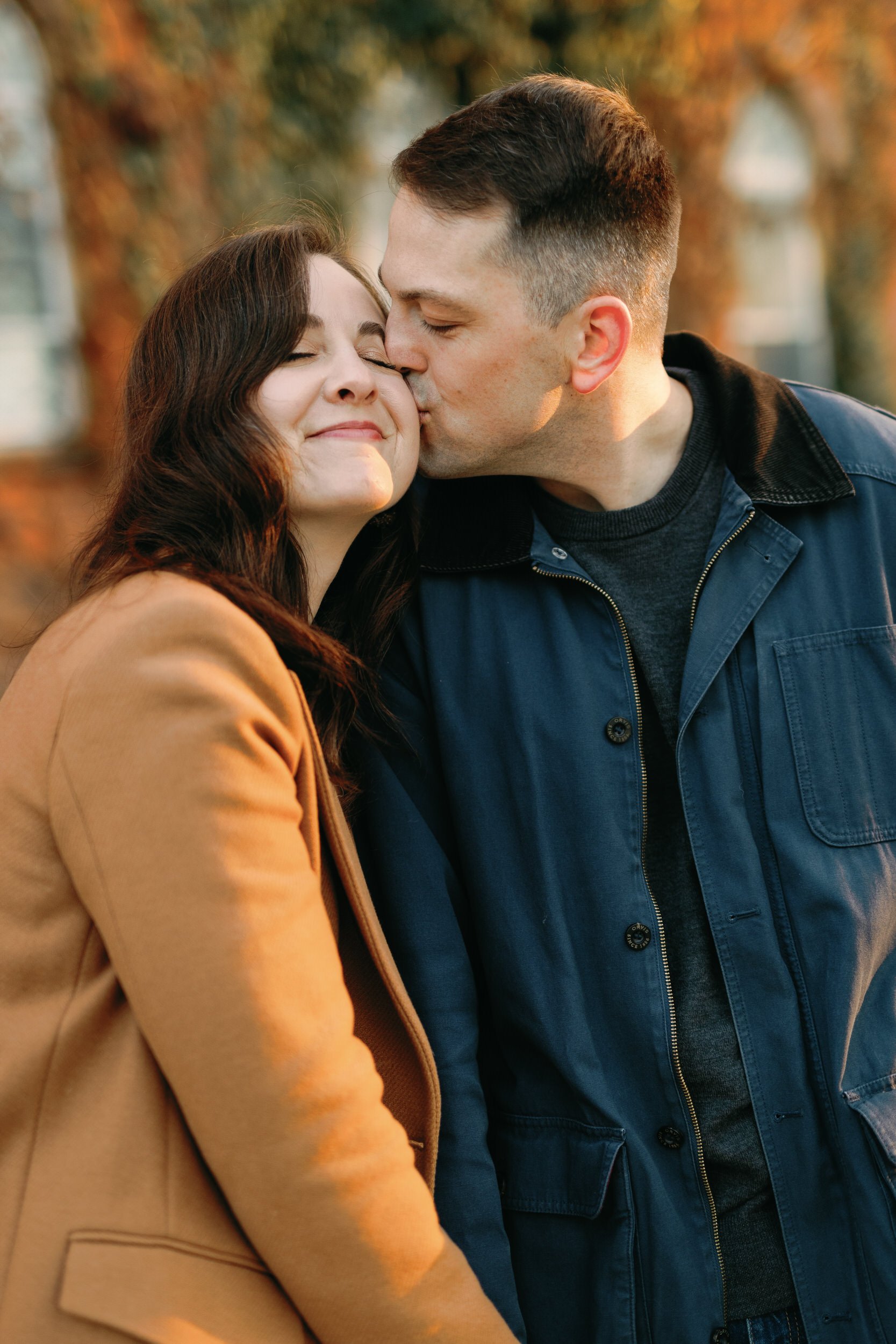 A person kissing their partner's cheek as they smile 