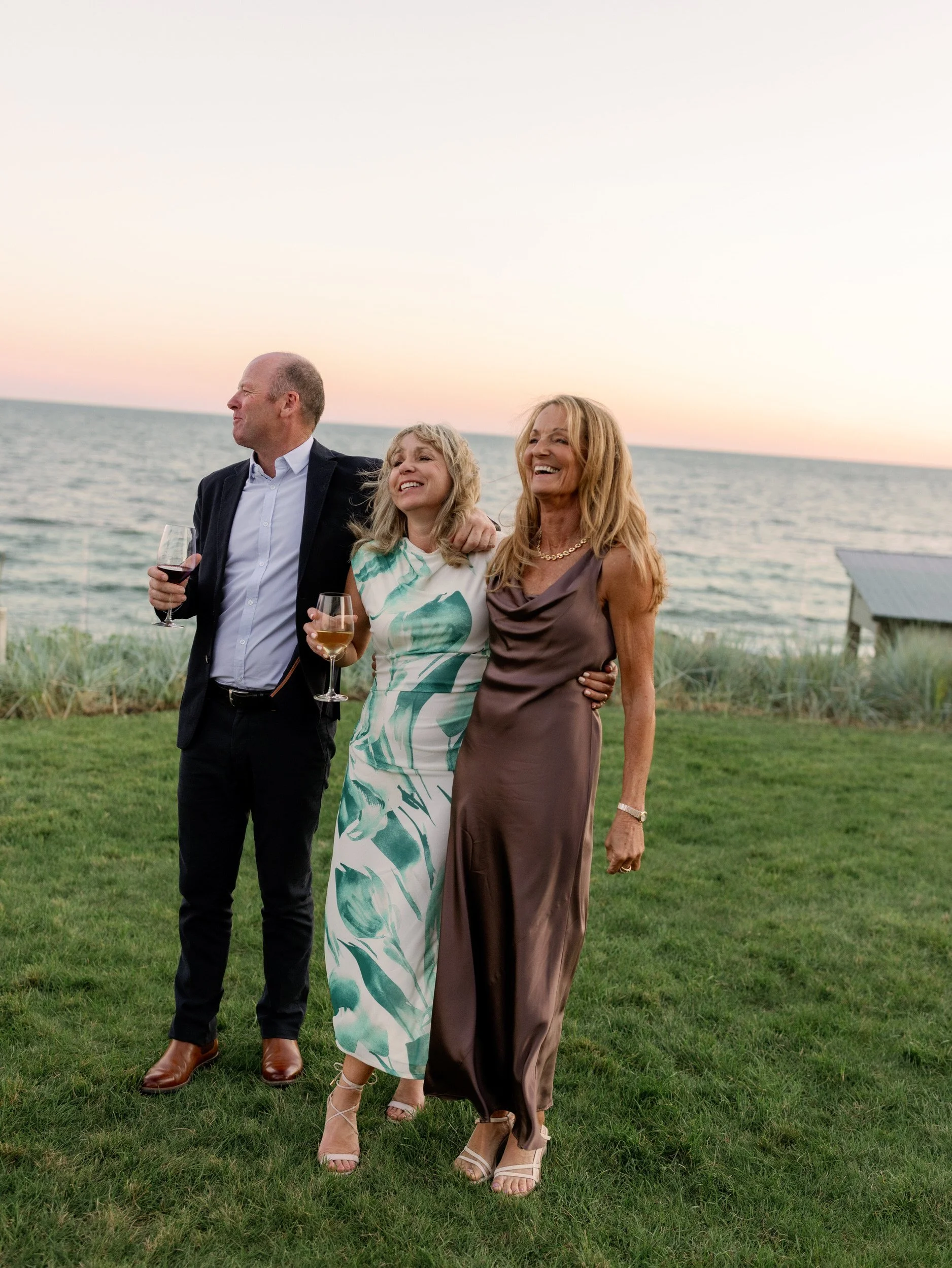 Wedding guests laughing as they stand out on a lawn 