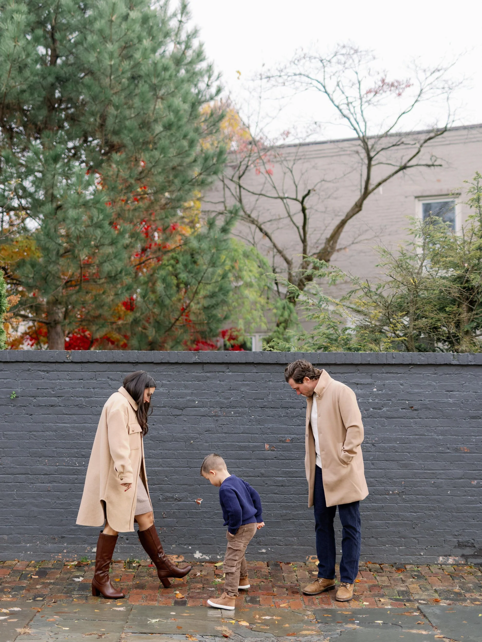 Parents looking down and stomping on leaves with their child 