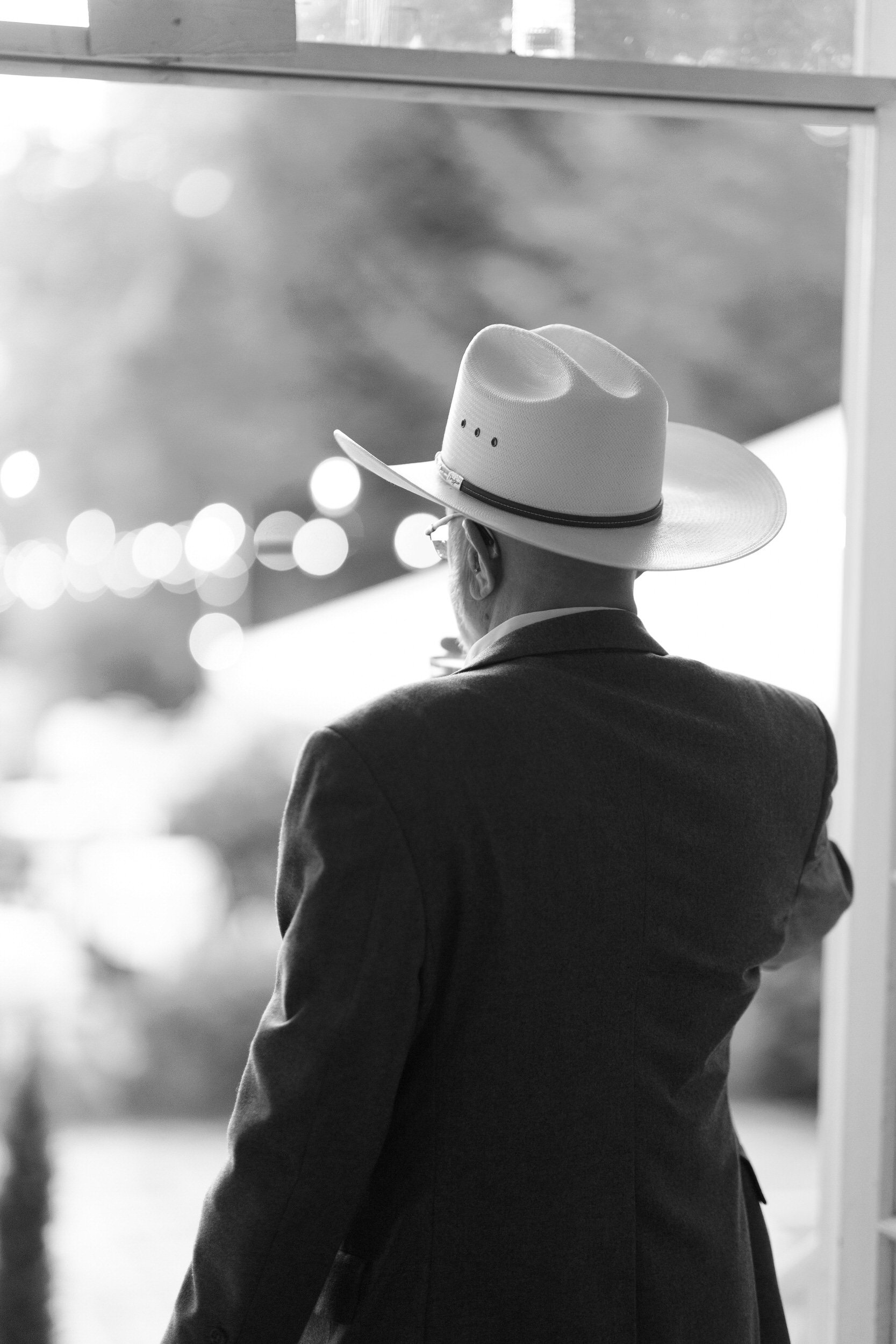 A person in a suit and a white cowboy hat 